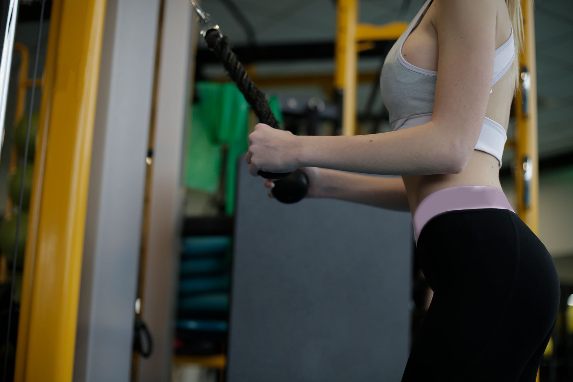 Fit woman working out with cable machine in gym for strength and fitness training.