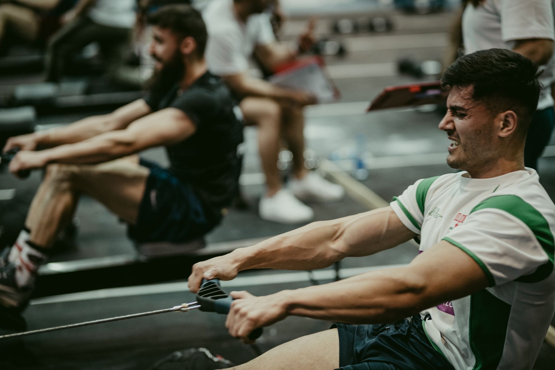 Focused athletes engaged in a high-intensity rowing session in the gym, showcasing strength and endurance.