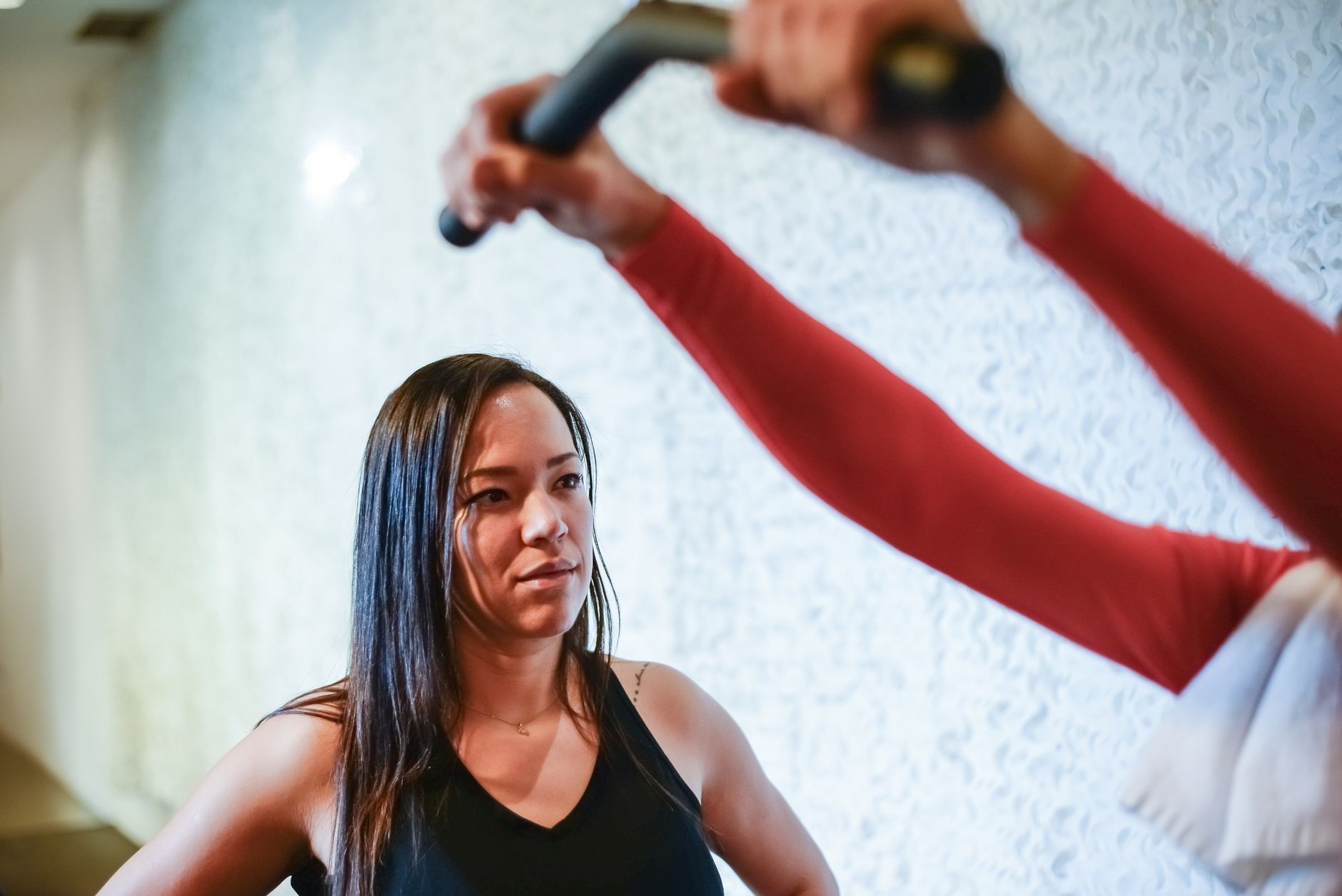 A focused woman receives guidance from a trainer during a gym workout in Portugal.