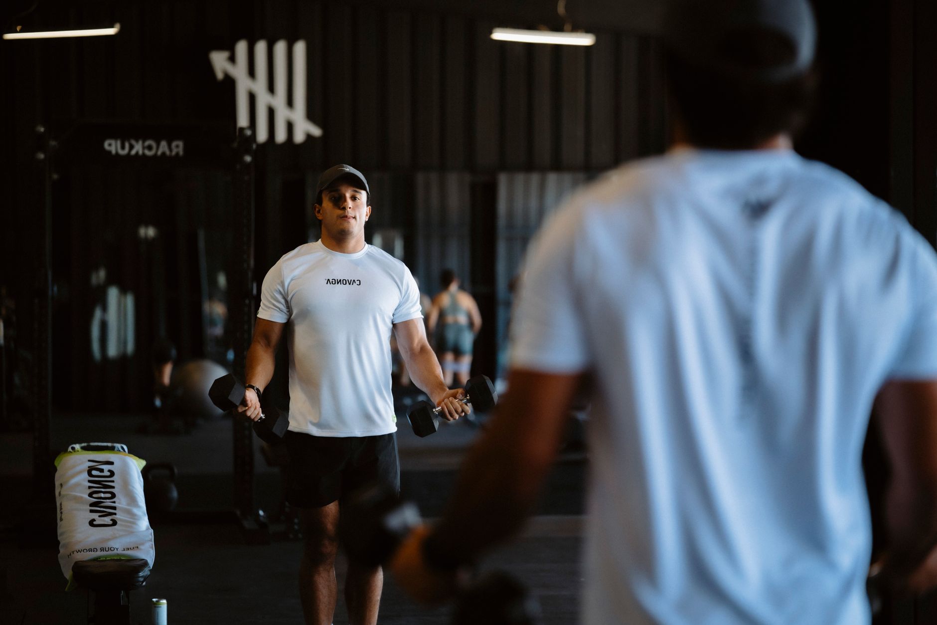 A man lifting weights in a mirror at a modern gym reflecting his fitness focus.