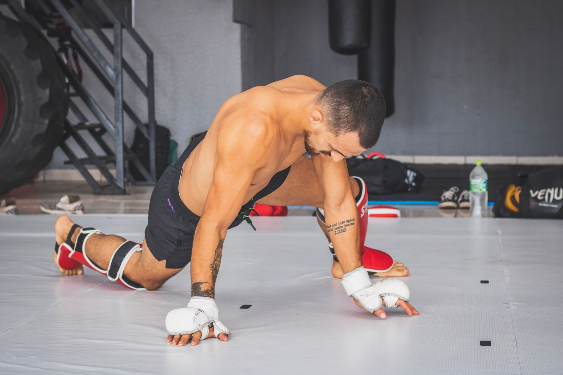A martial arts athlete performing stretching exercises in a gym setting.