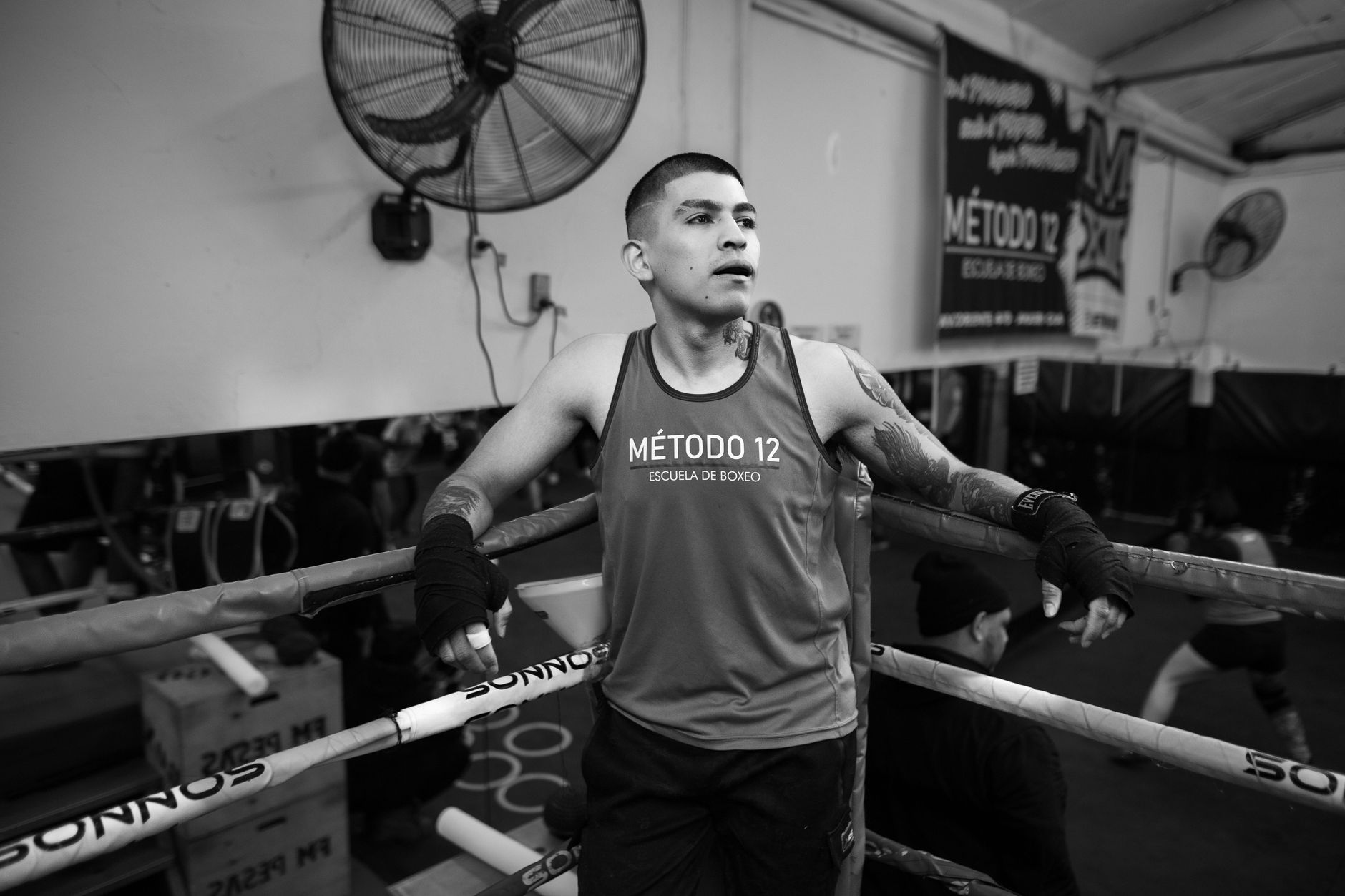 Black and white photo of a boxer resting in a gym ring at Método 12, Buenos Aires.