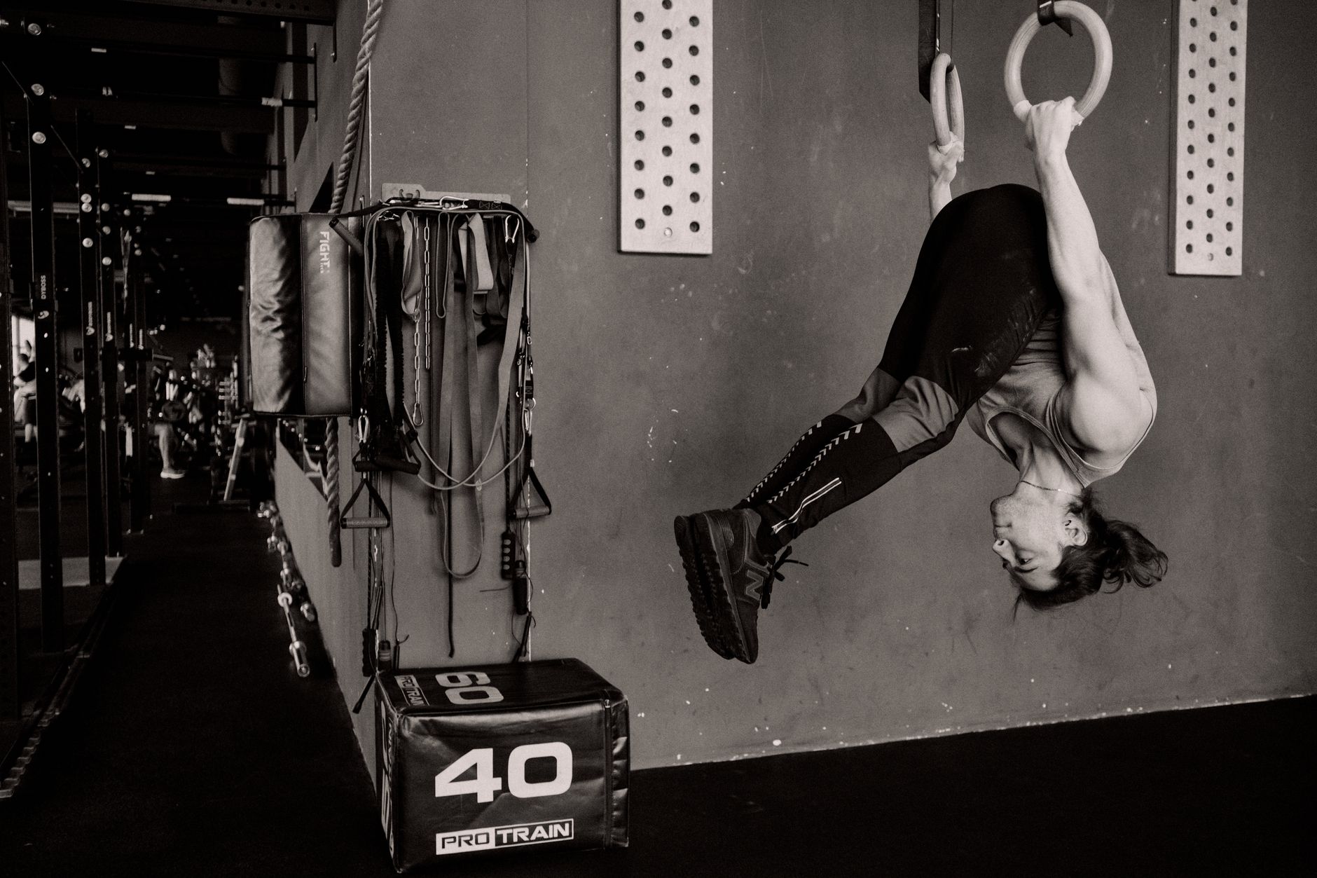 A man showcasing strength with a handstand on gymnastic rings in a gym setting.