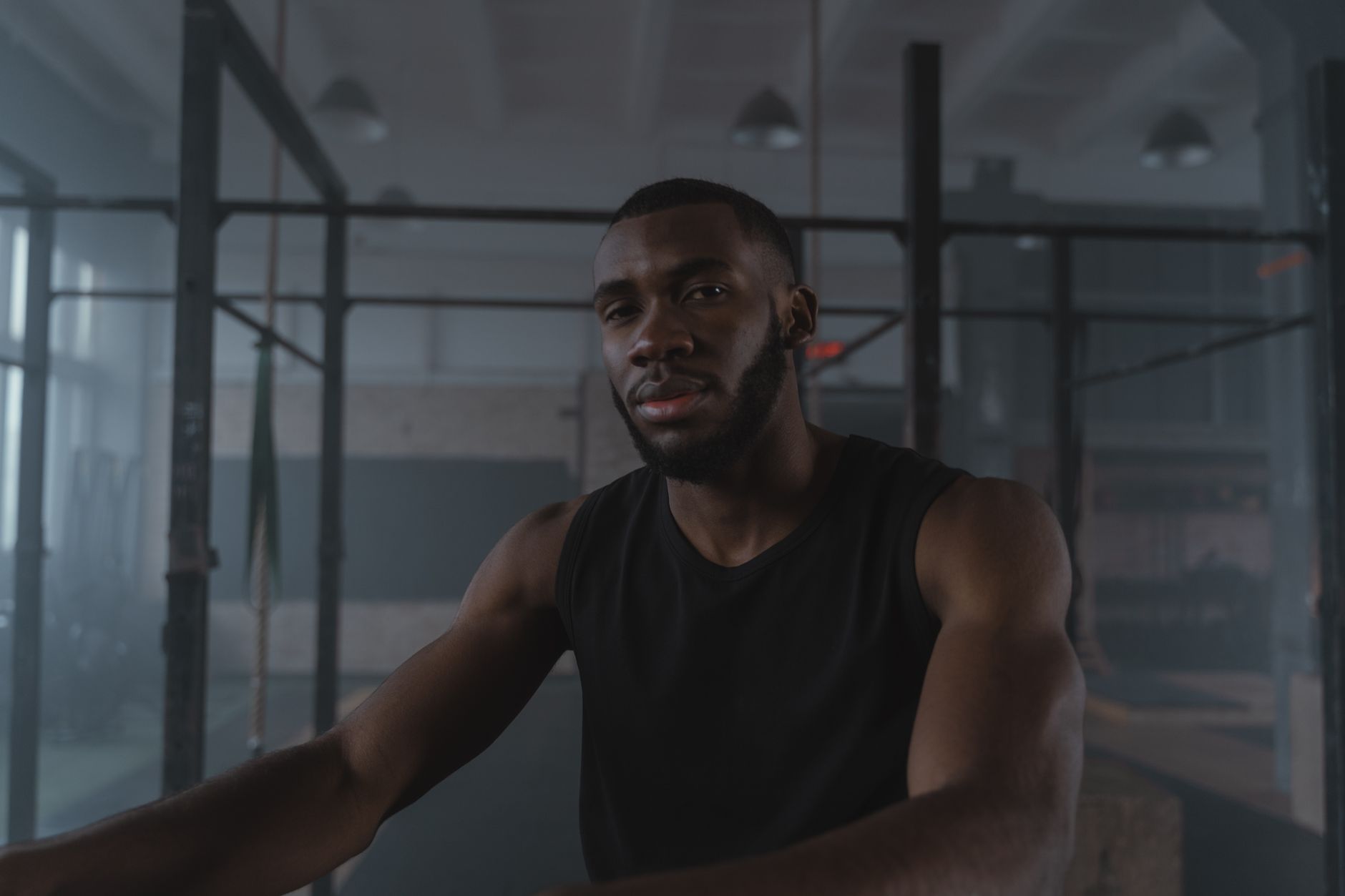 Portrait of a bearded man in a black tank top at the gym, expressing confidence.