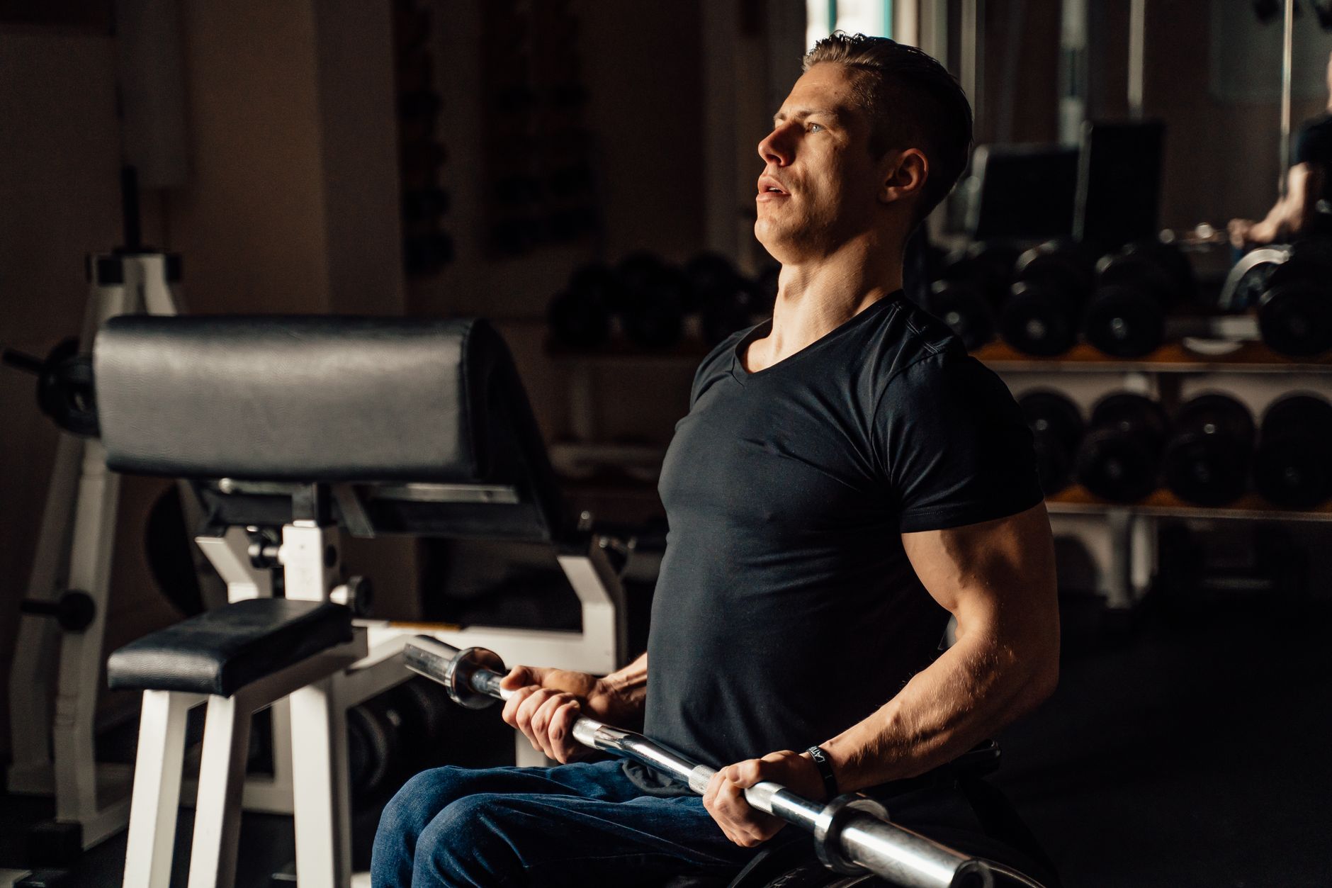 Strong disabled man exercising in gym using barbell. Focus on fitness and determination.