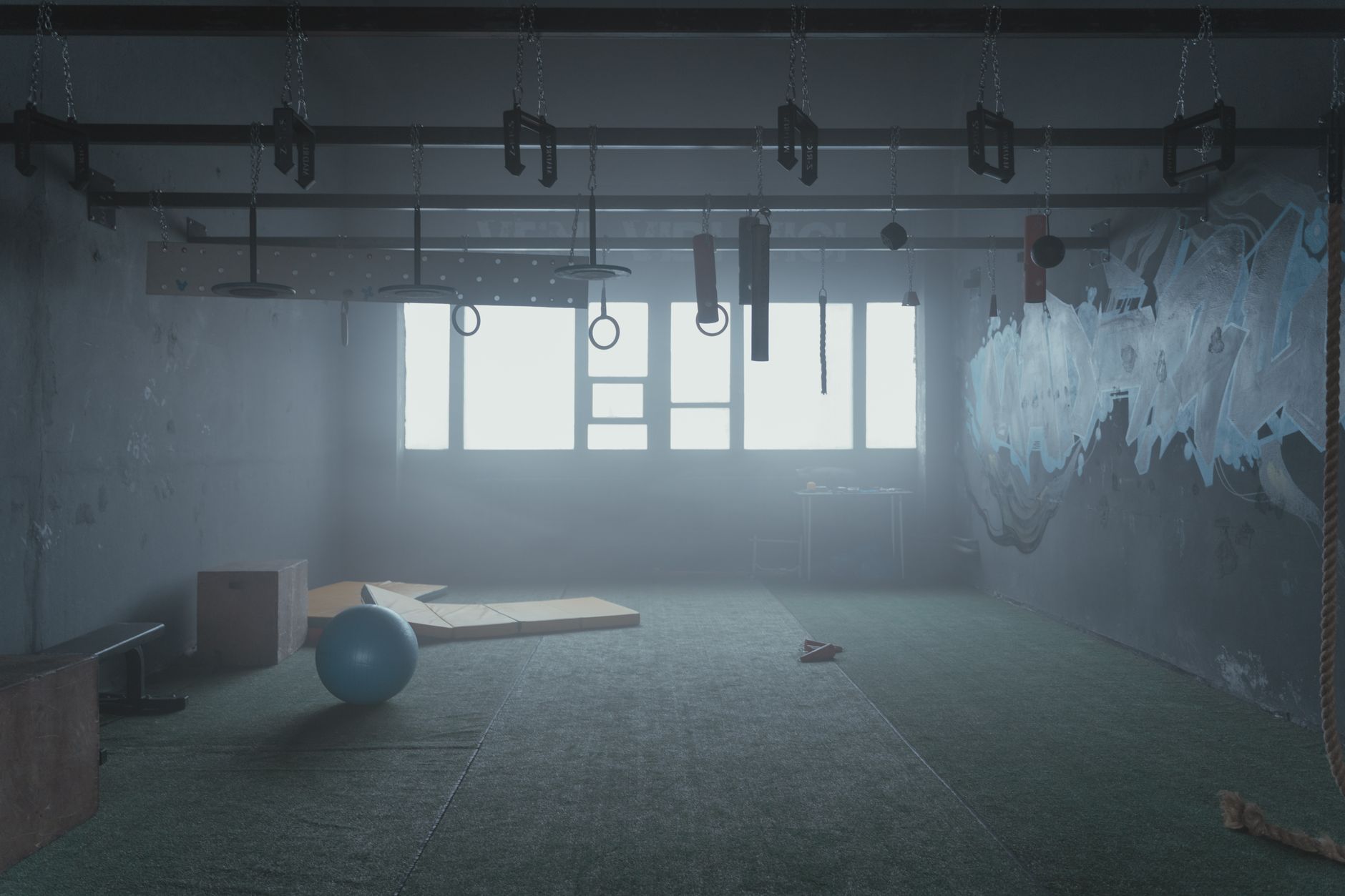 Empty industrial-style gym room with functional fitness equipment and natural lighting.