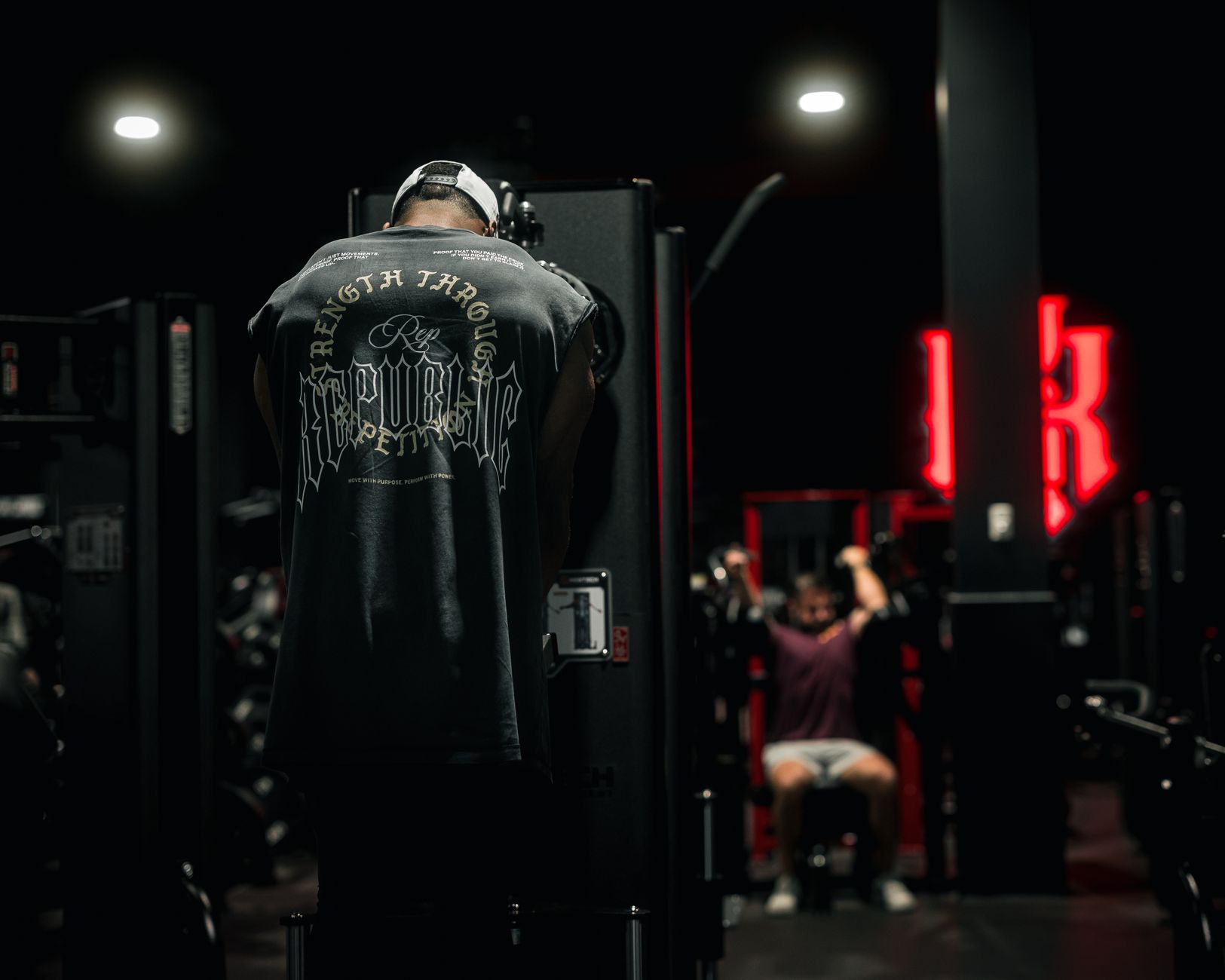 A focused gym-goer exercises in a dimly lit gym, embodying strength and determination.