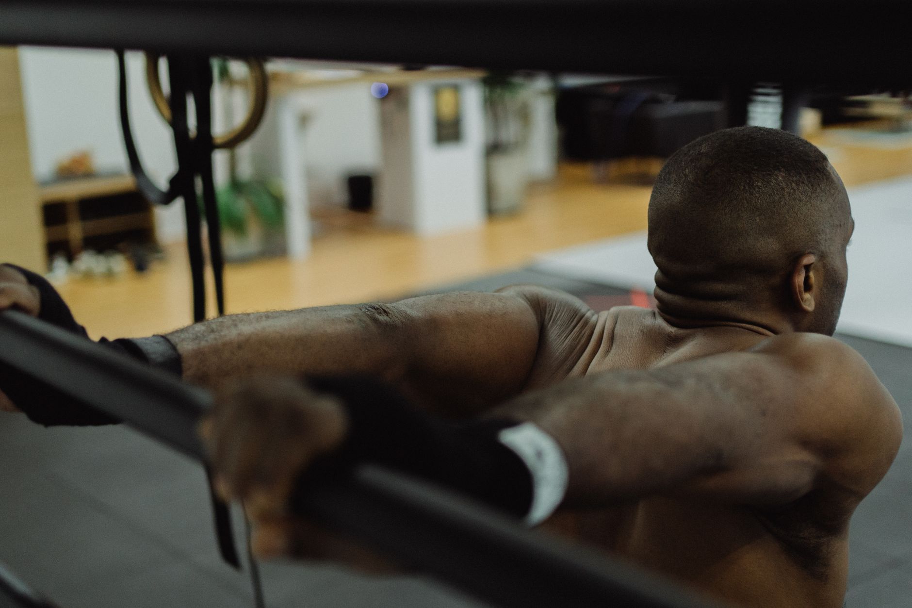 Close-up of a shirtless man lifting a barbell in a gym, showcasing strength and fitness focus.