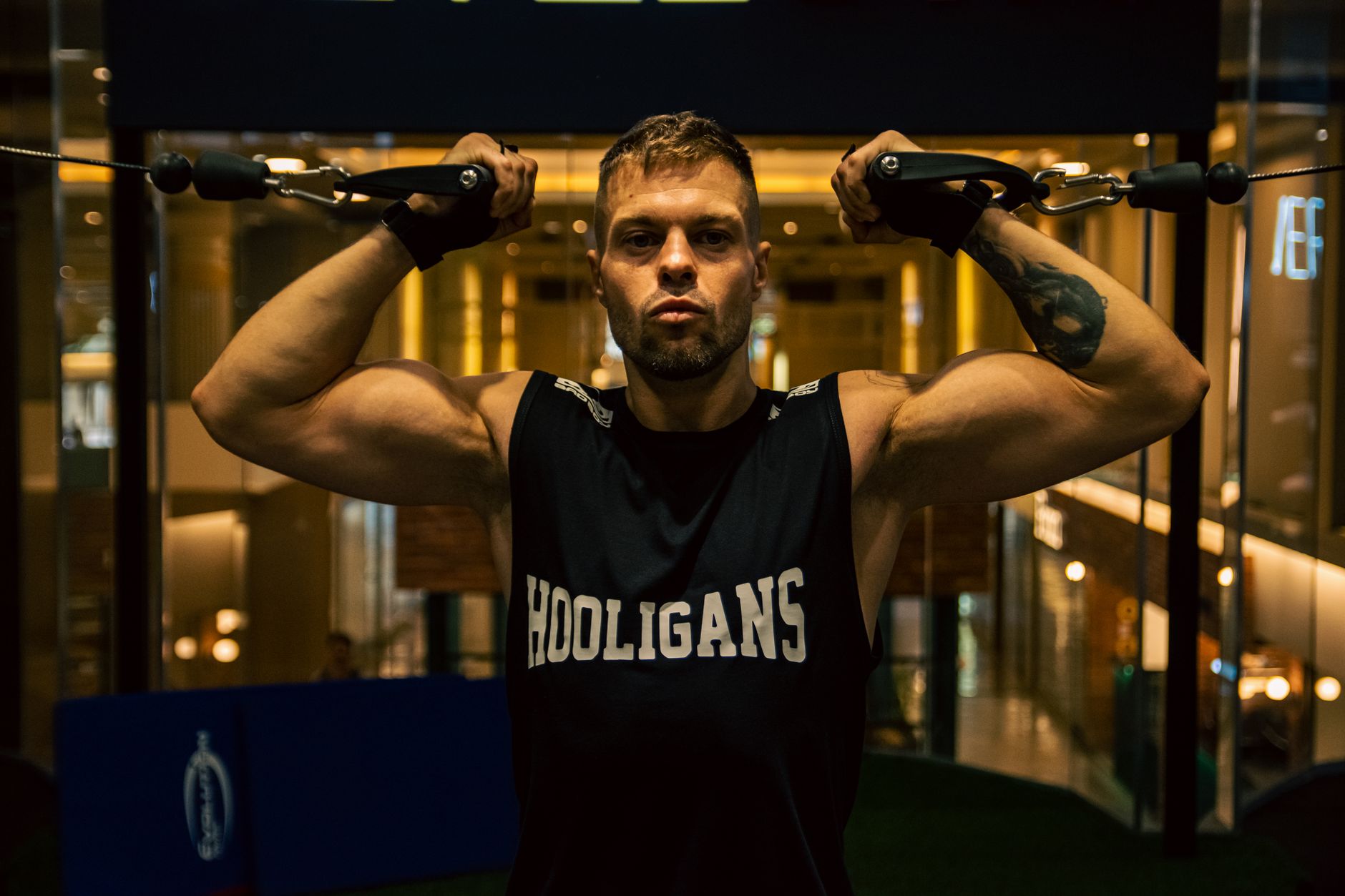 Muscular man working out with a cable machine in an indoor gym setting, focusing on strength training.
