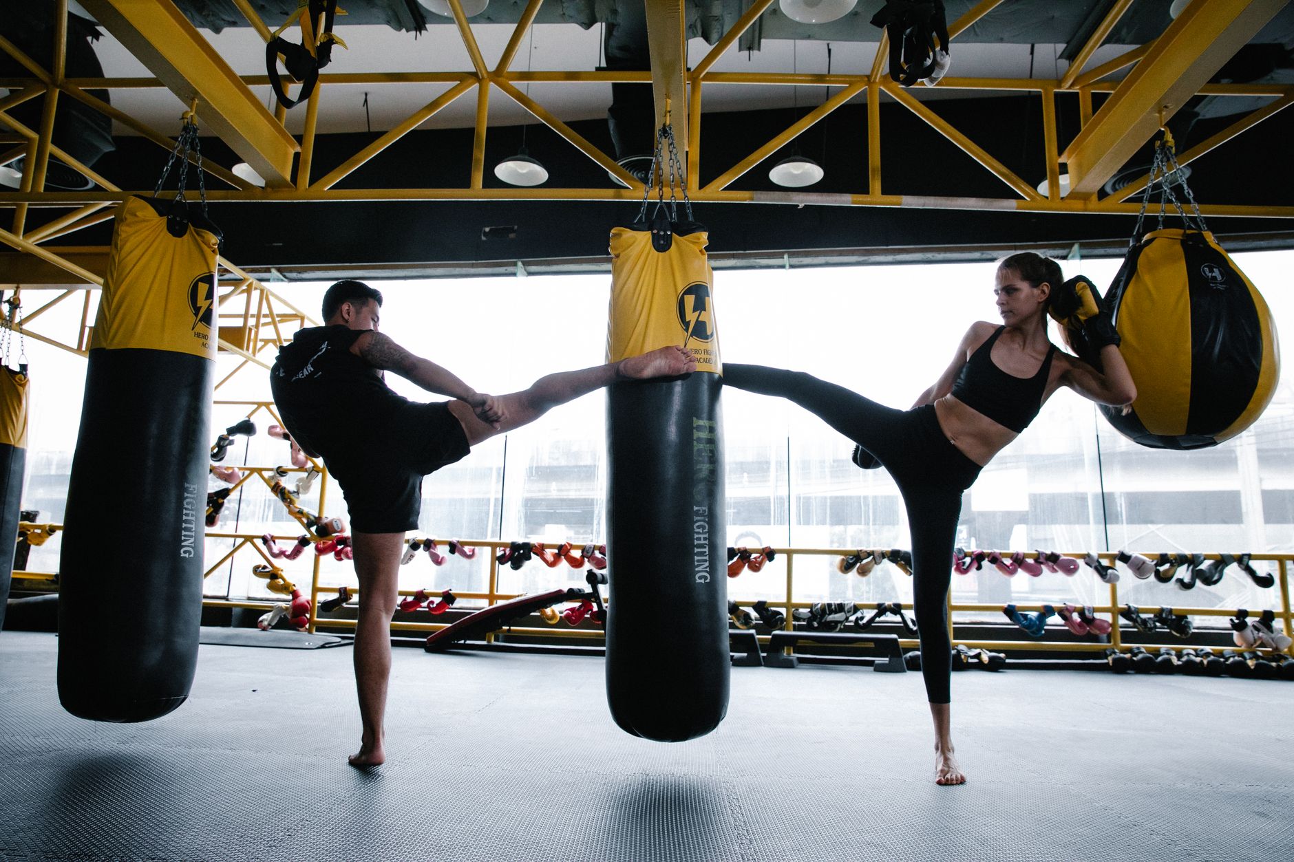 Two adults engaging in a high-energy kickboxing workout indoors with punching bags.