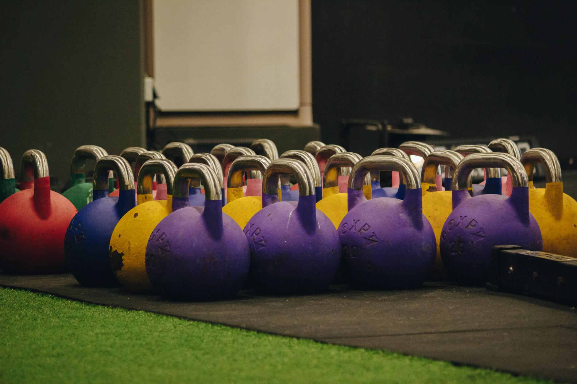 Vibrant kettlebells neatly arranged on the gym floor, ready for workout sessions.