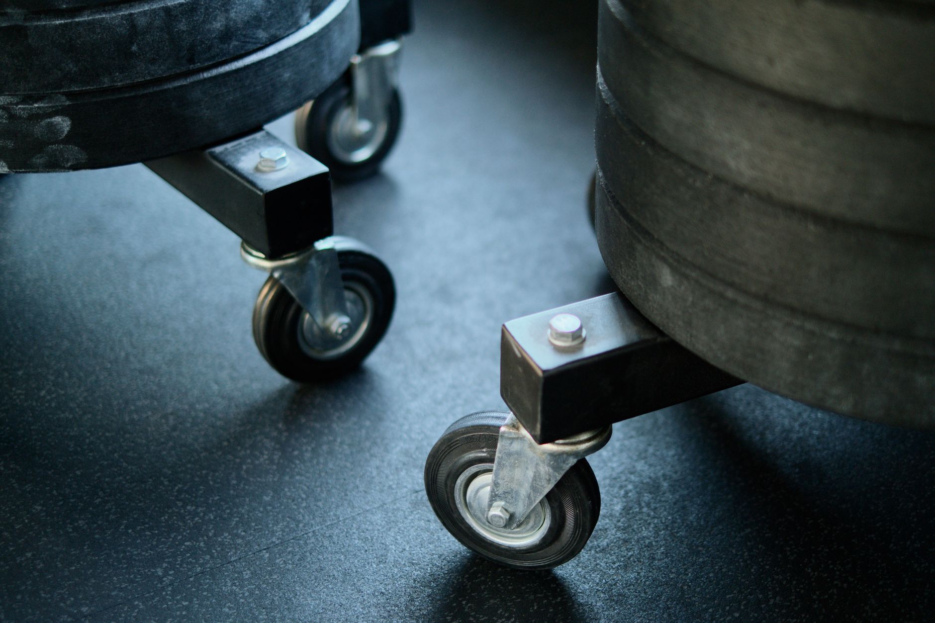 Wheels of gym equipment close-up on a black gym floor, showcasing industrial design.