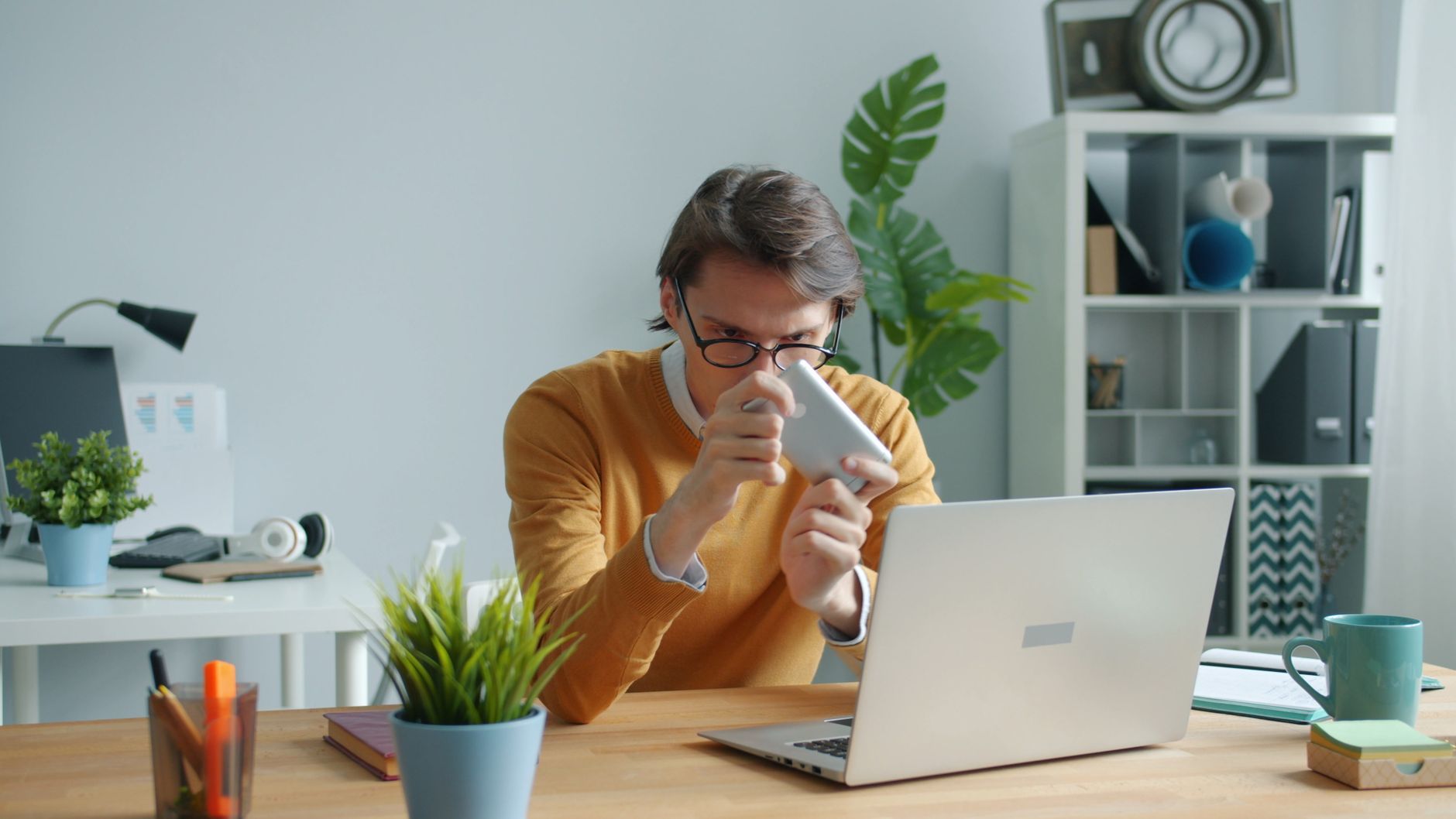 Young man sipping coffee while working from home on his laptop.