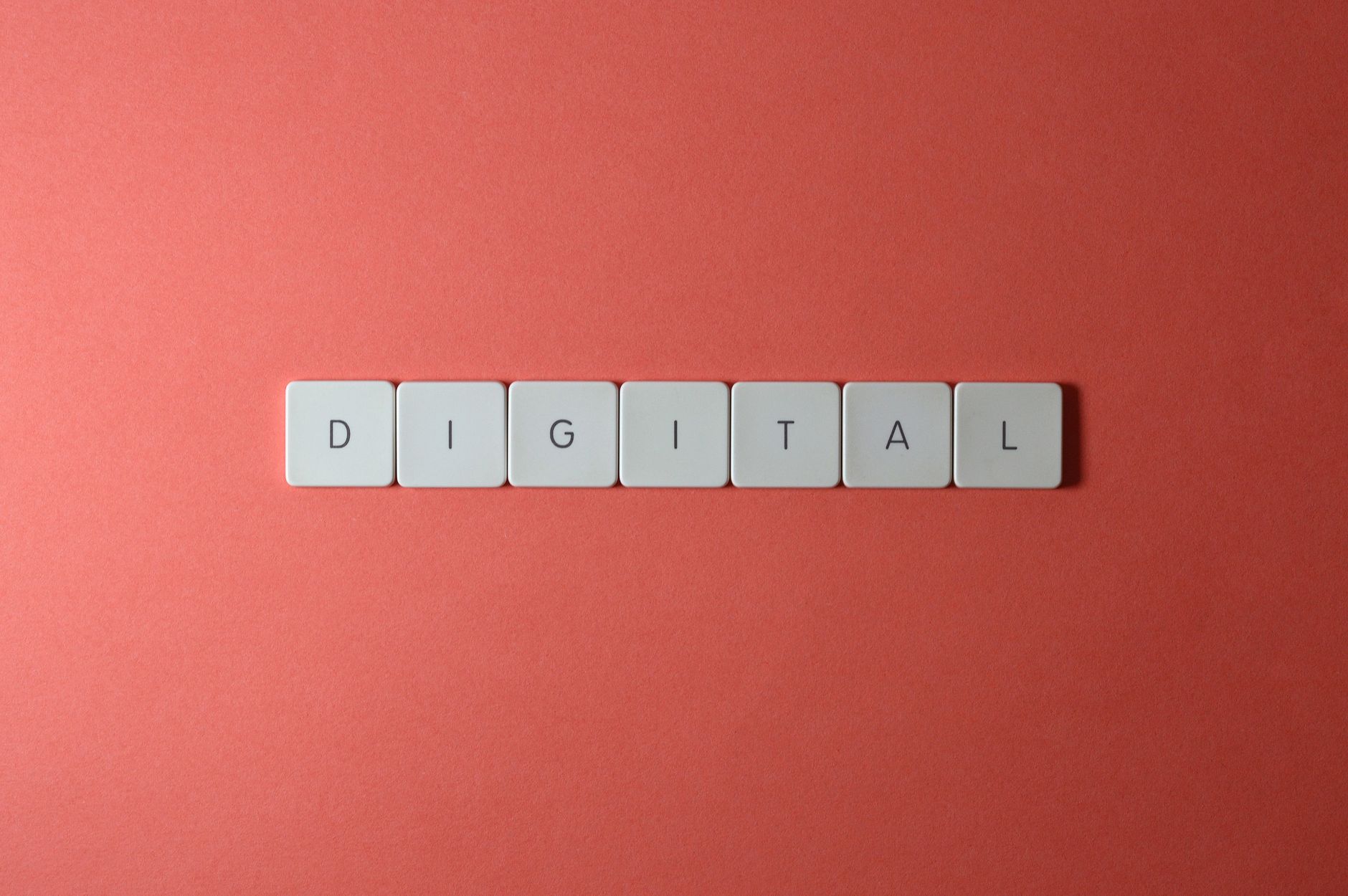 Close-up of keyboard tiles spelling 'DIGITAL' on a red background, perfect for tech themes.