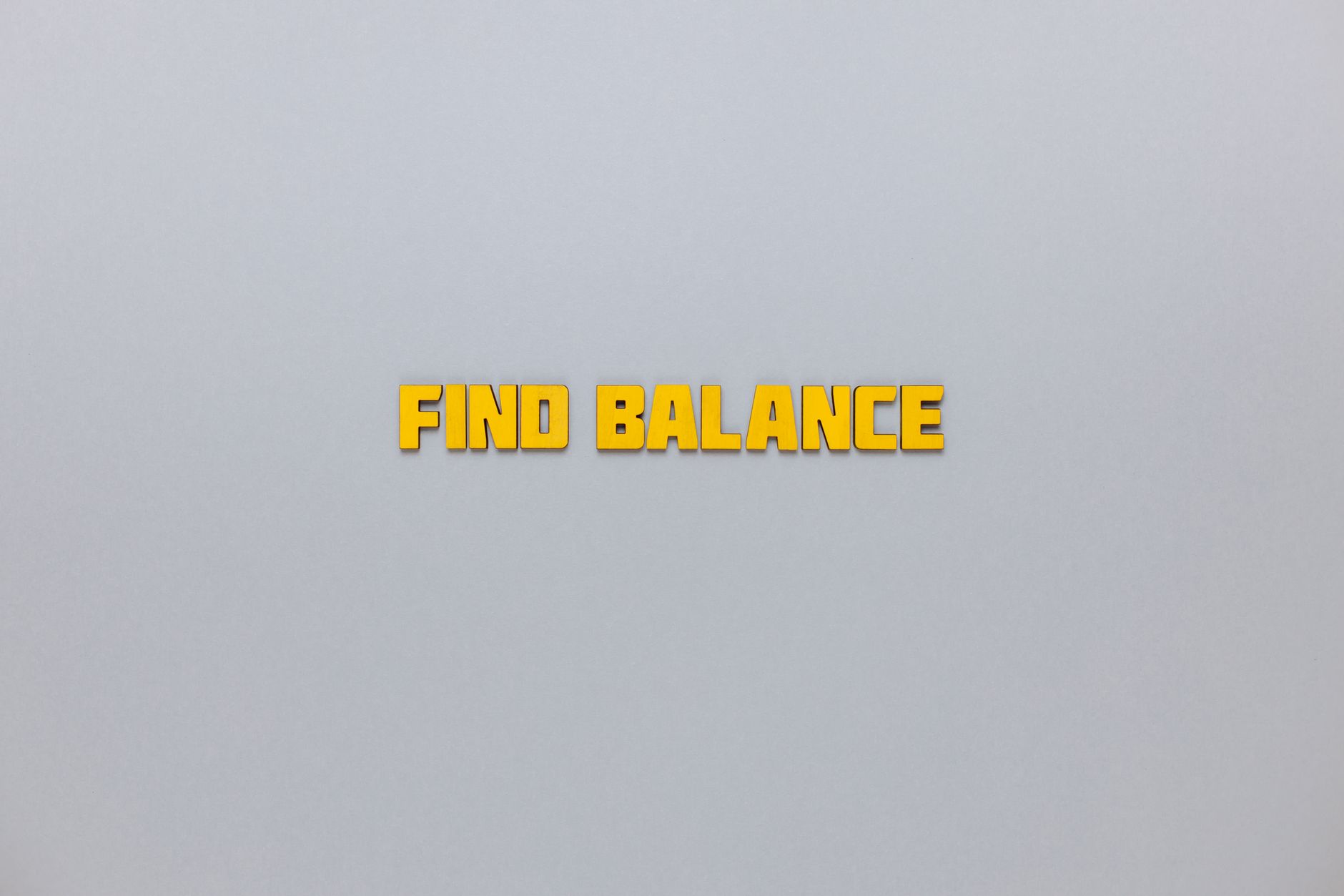 Yellow text 'Find Balance' displayed on a minimalist grey backdrop for motivation.