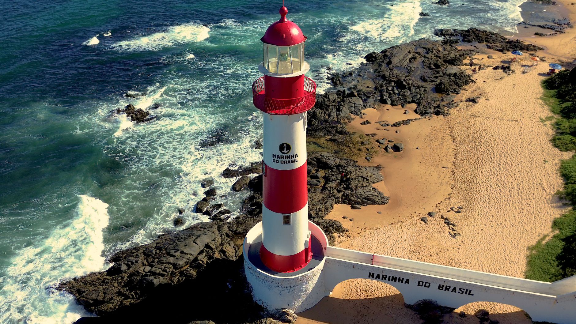 A stunning aerial shot of the Barra Lighthouse in Salvador against a rocky coastline.