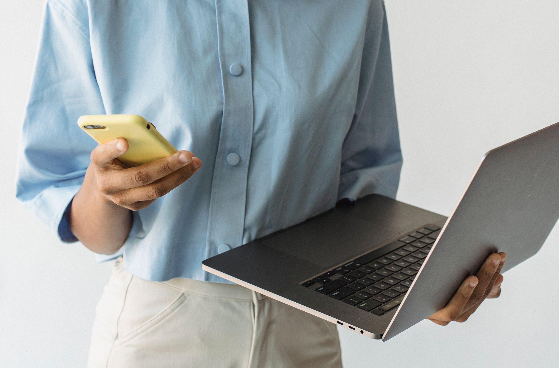 Close-up of a person multitasking with a laptop and smartphone, emphasizing technology use.