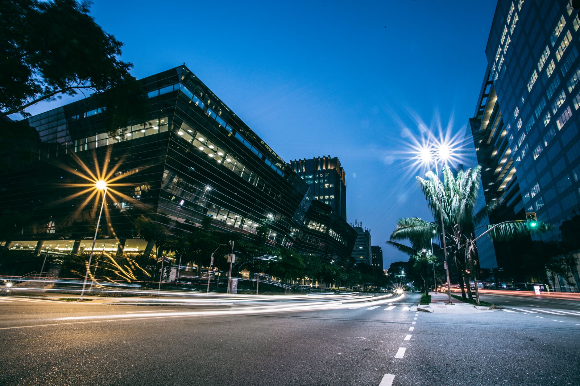 Long exposure of city street with modern buildings and bright street lights at night.