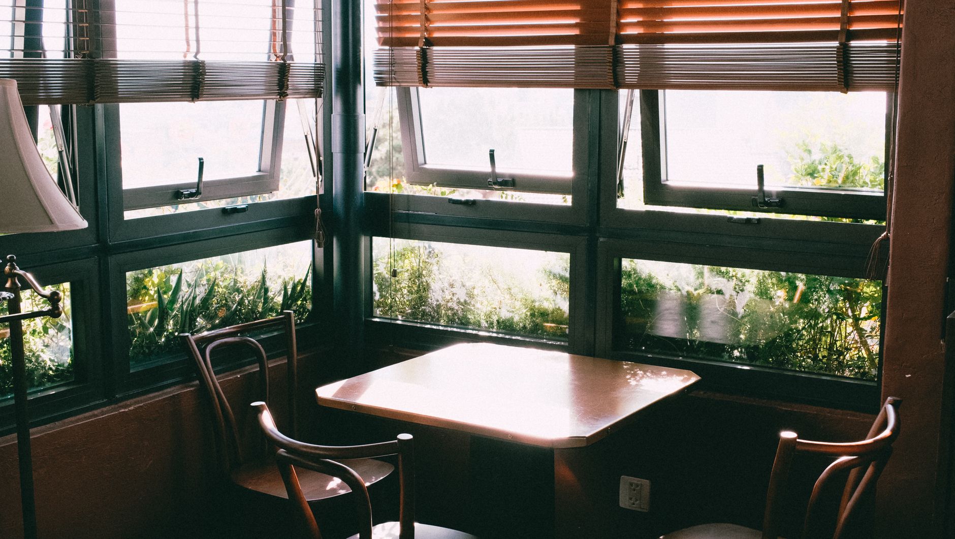 Sunlit dining corner with classic chairs and wooden blinds for a warm and inviting atmosphere.
