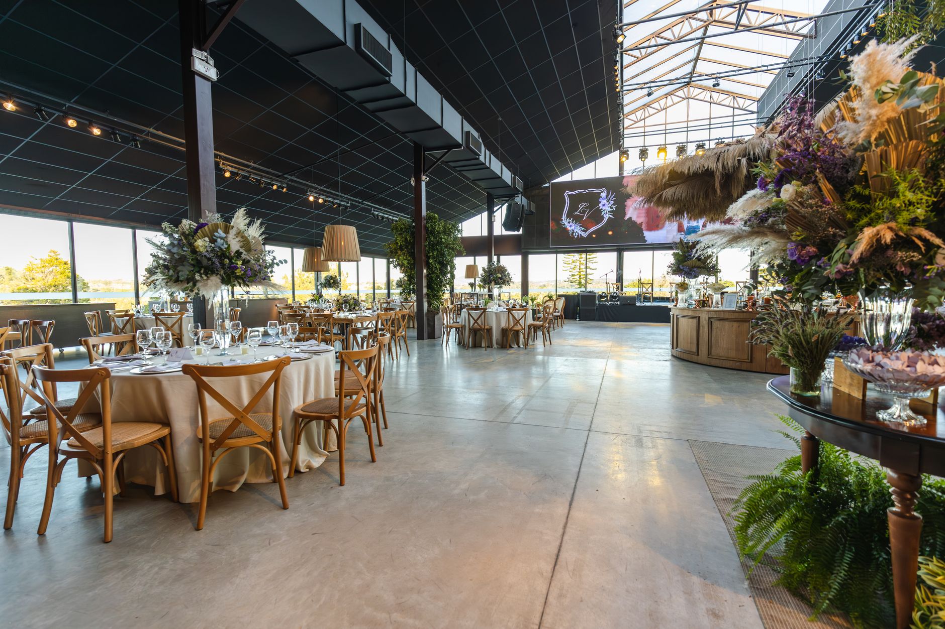 Spacious wedding reception venue featuring elegant floral decor and wooden furniture, perfect for special occasions.