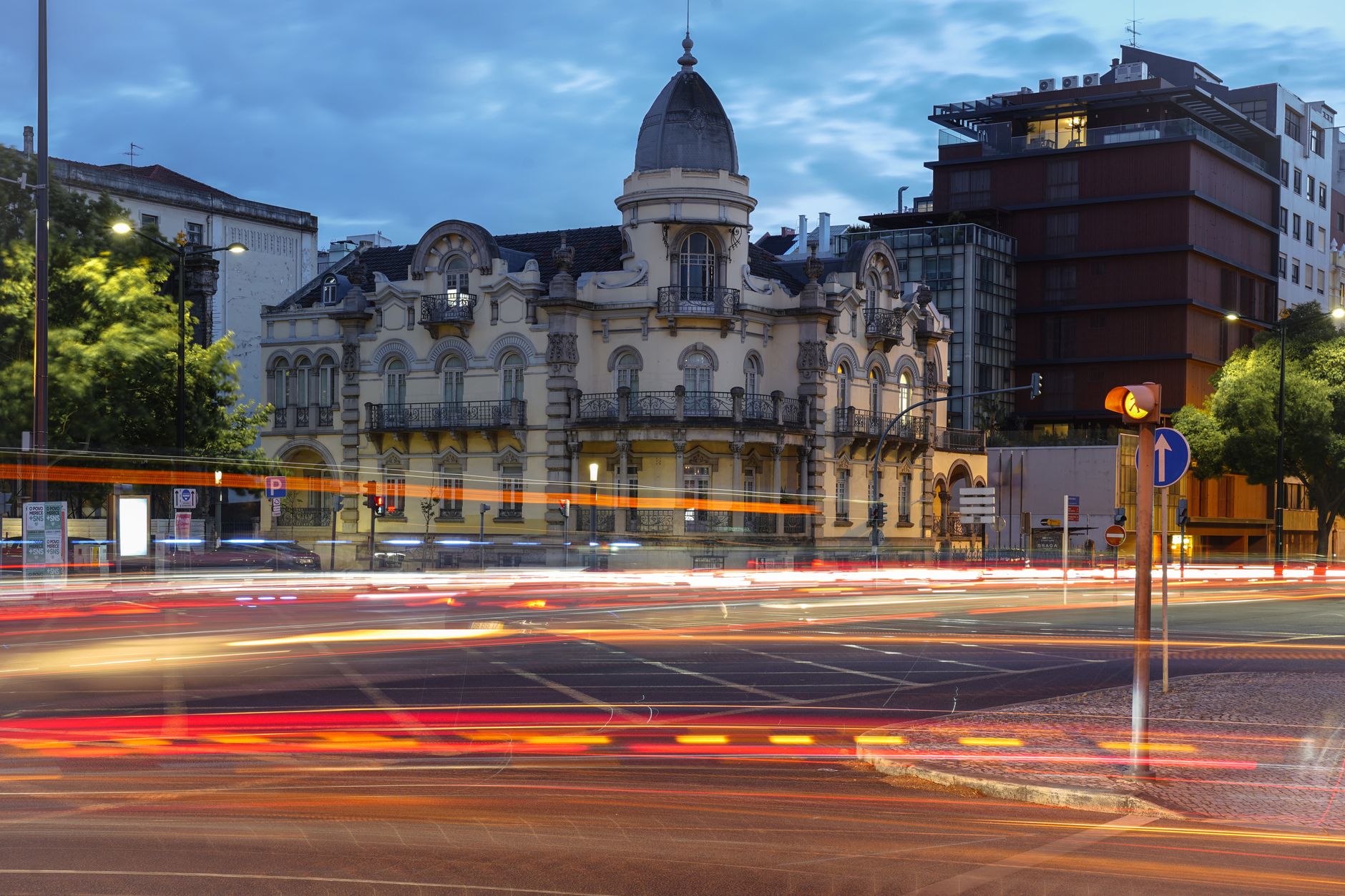 A vibrant urban scene of Lisbon with a historic building and light trails at twilight.