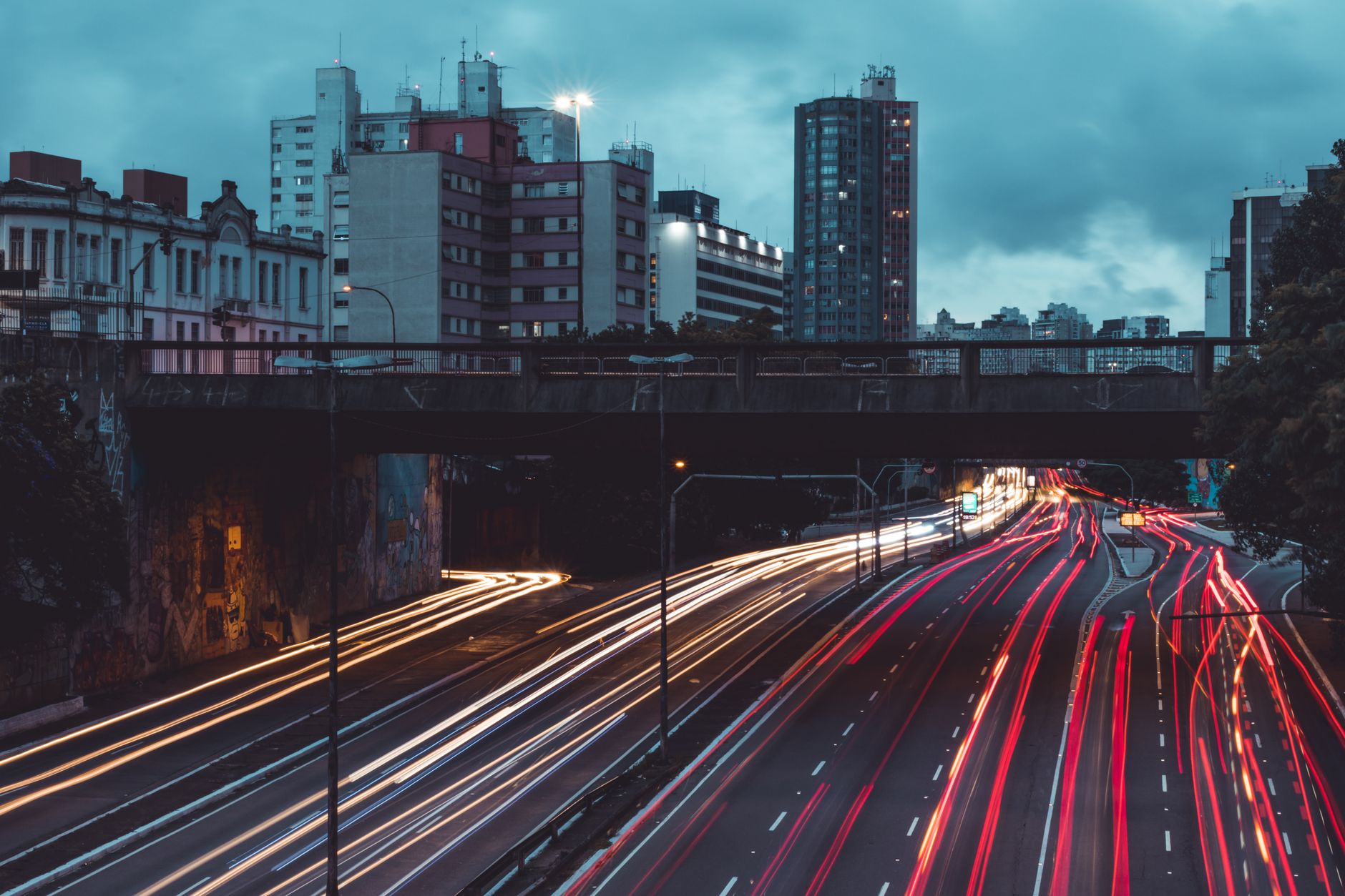 Long exposure night shot of urban traffic, revealing colorful light streaks under cloudy skies.