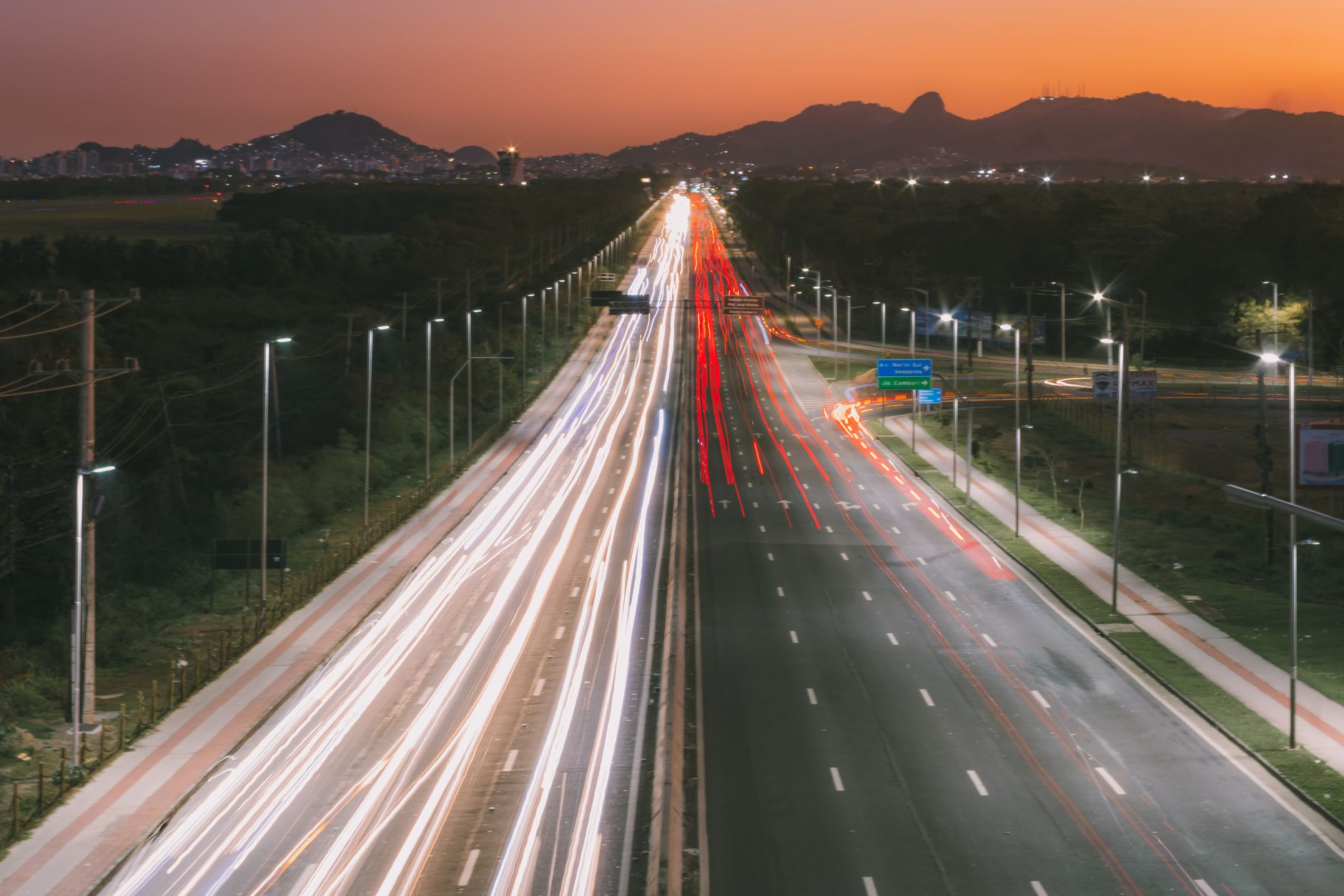 Aerial view of a bustling city highway at sunset with vibrant light trails creating a dynamic scene.