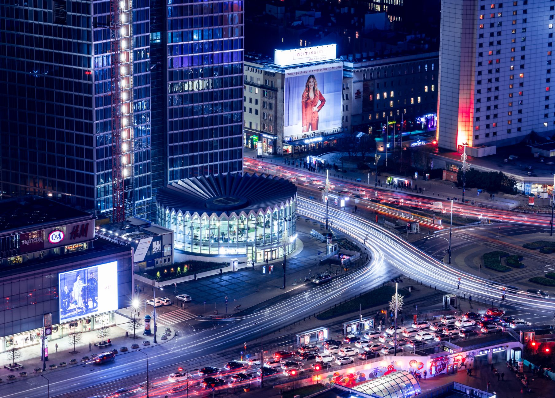 Aerial view of Warsaw cityscape with bustling traffic and illuminated buildings at night.