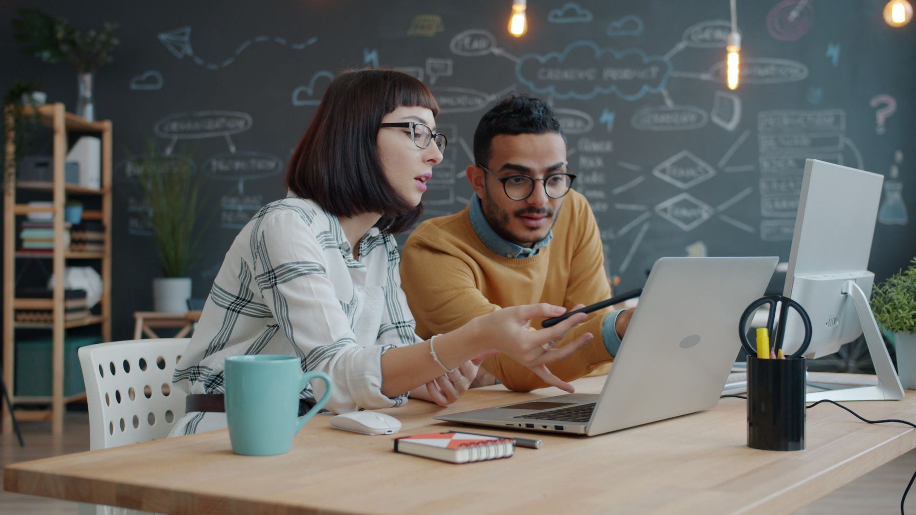 Two young professionals collaborating on a project in a modern office setting.
