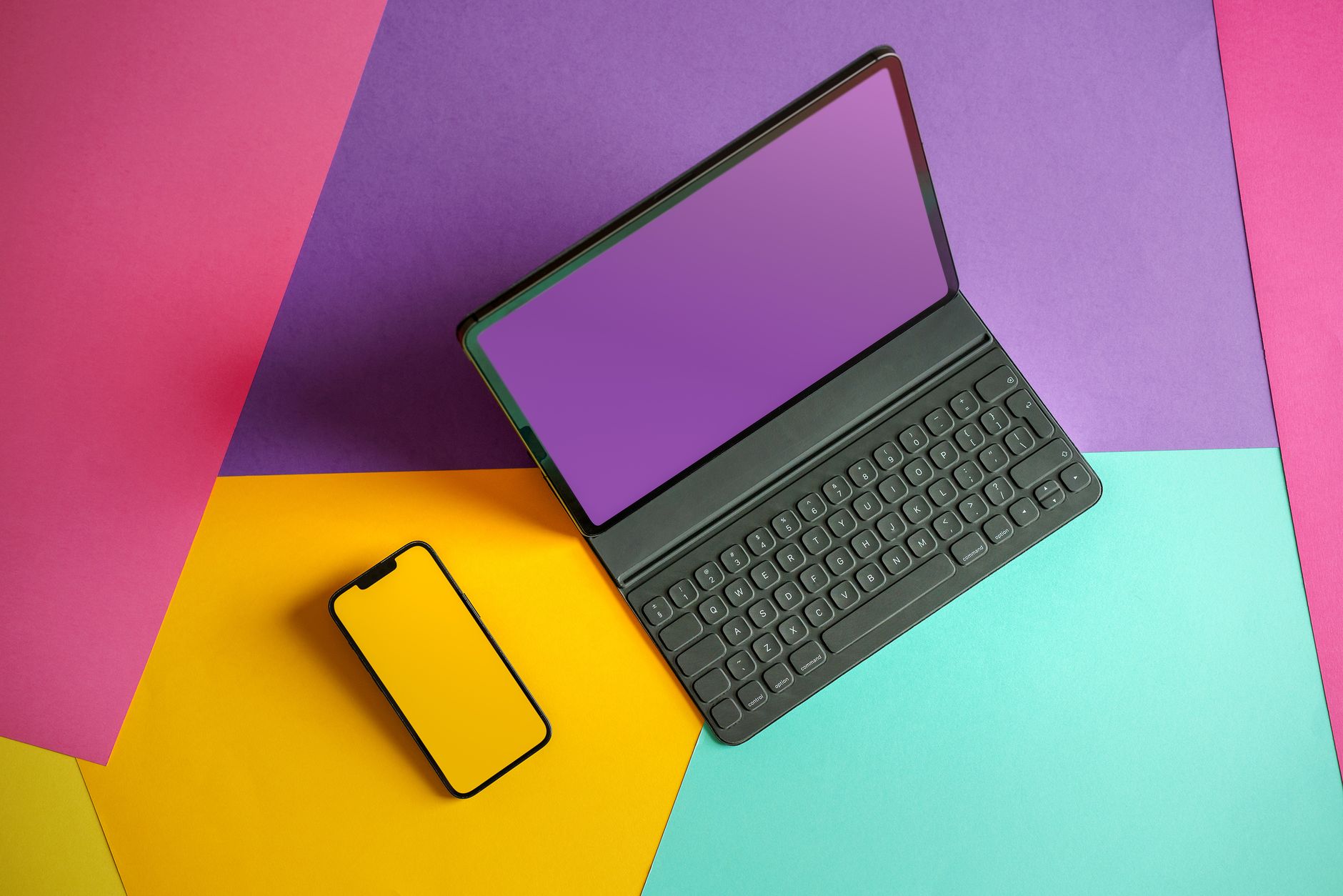 Top view of a laptop and smartphone on vibrant, colorful background, highlighting modern technology.