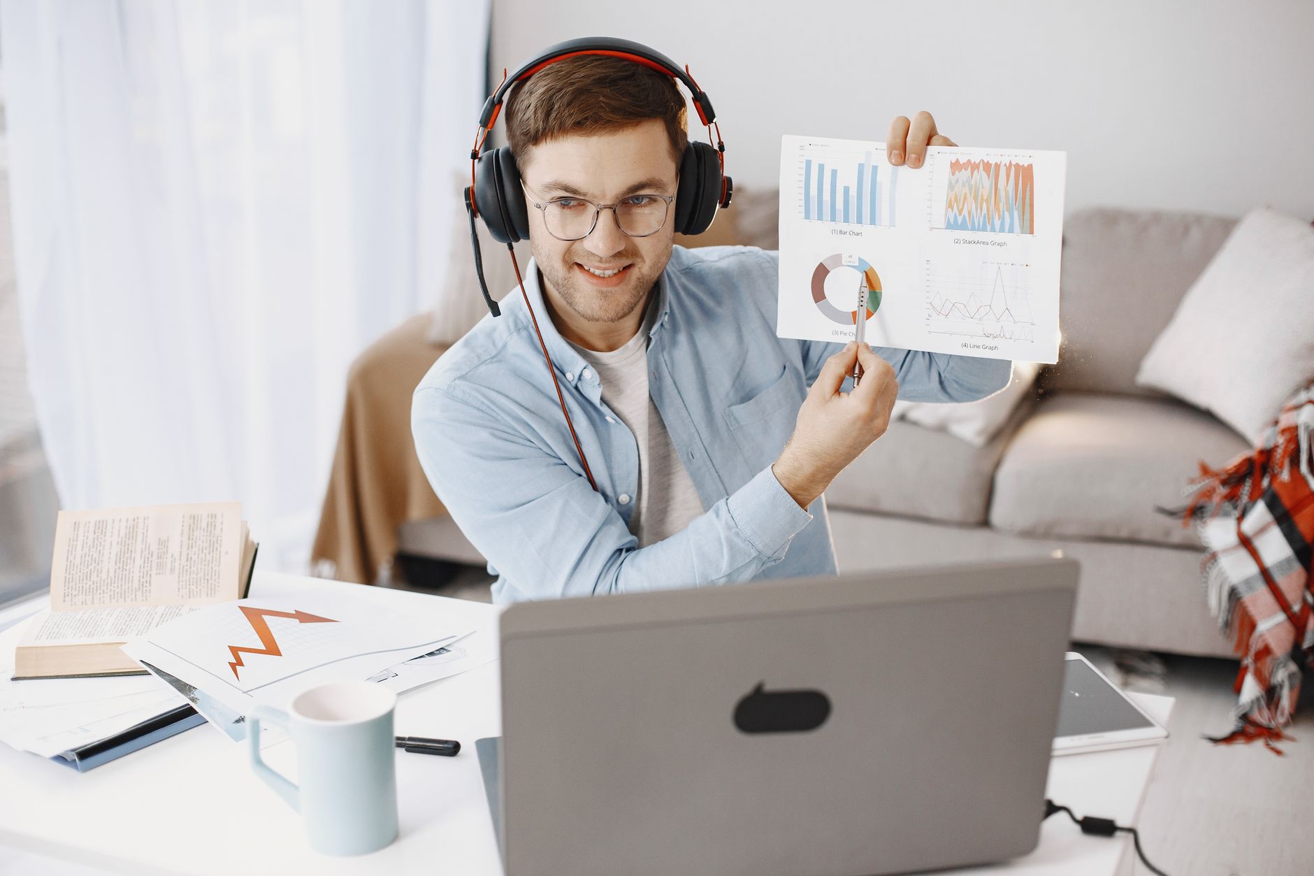 Man wearing headphones discussing charts during a remote work call at home office.