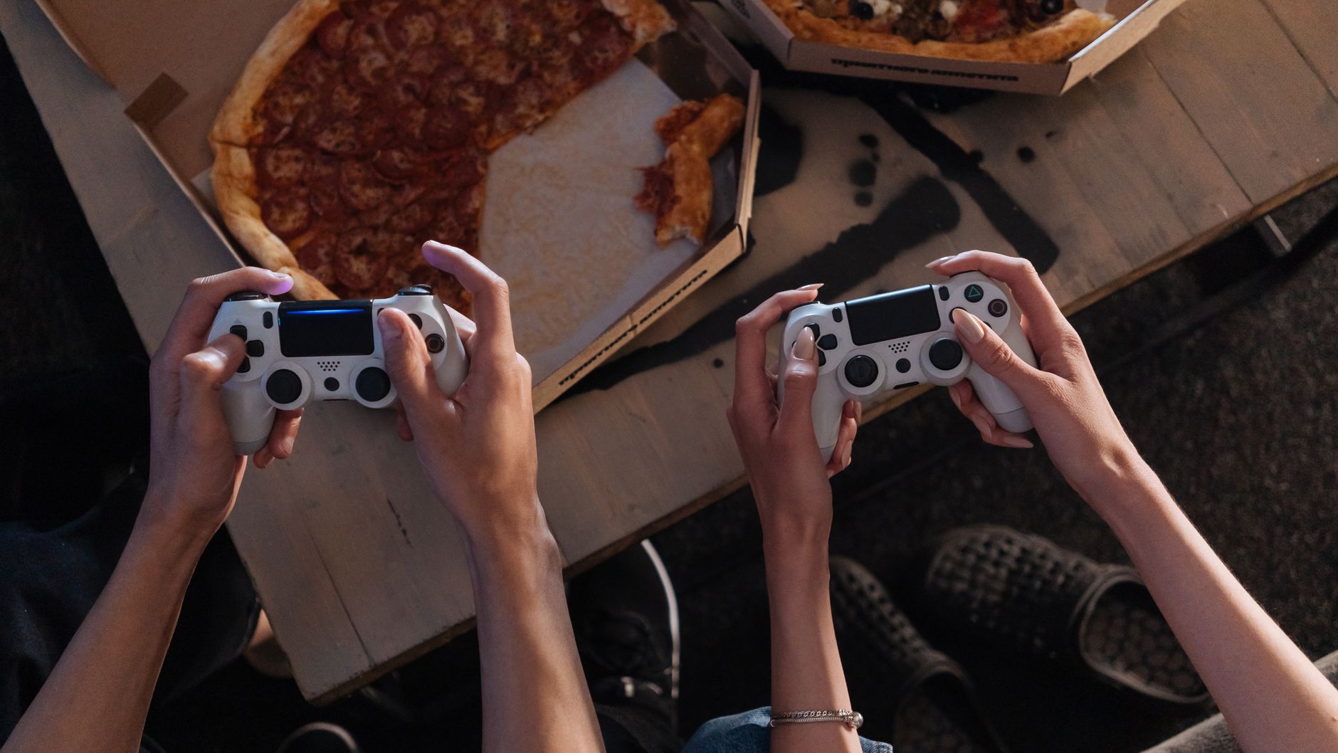 Two people enjoying a gaming session with pizza, creating a cozy and fun atmosphere.
