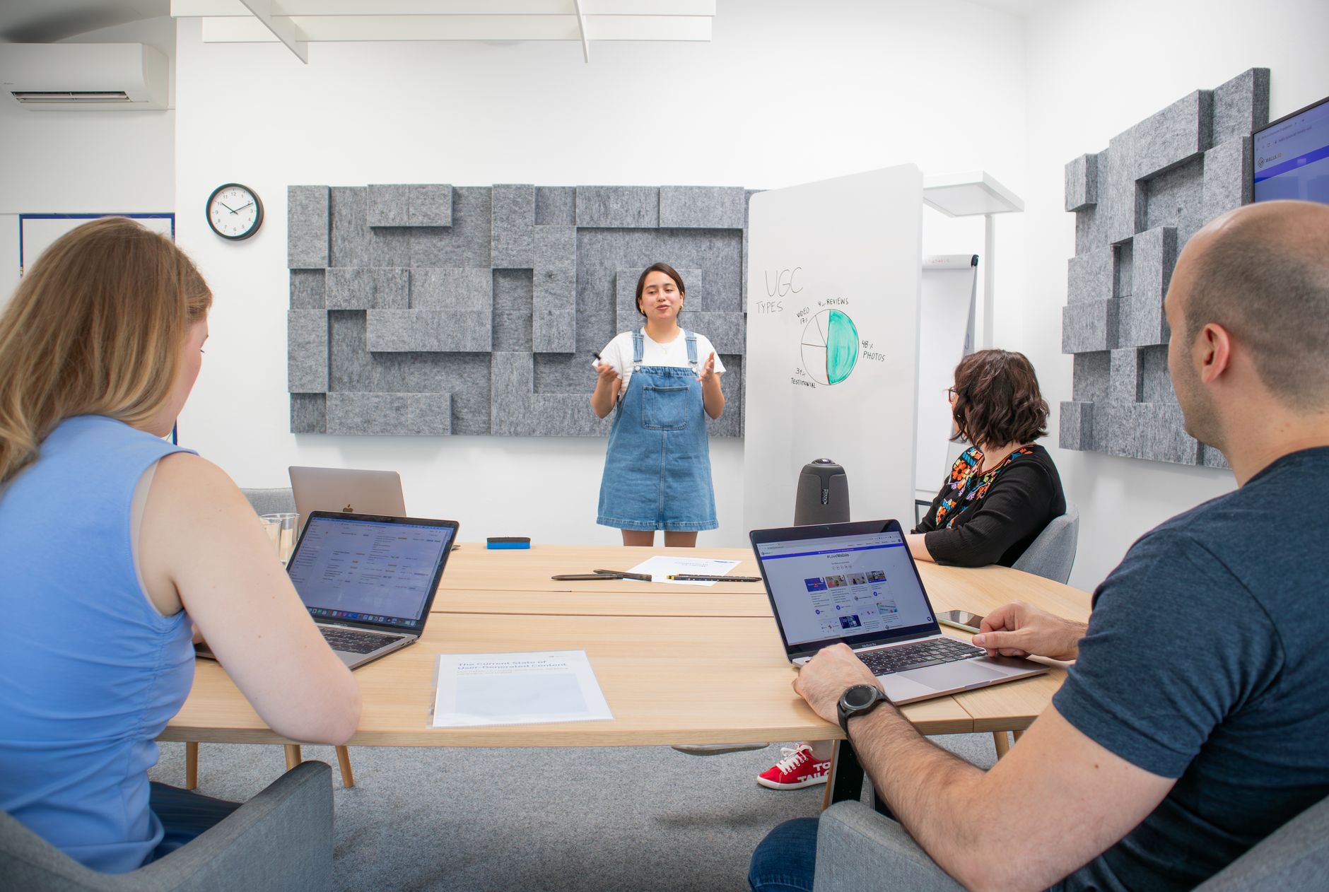 Team members engage in a collaborative meeting with laptops and presentation materials.