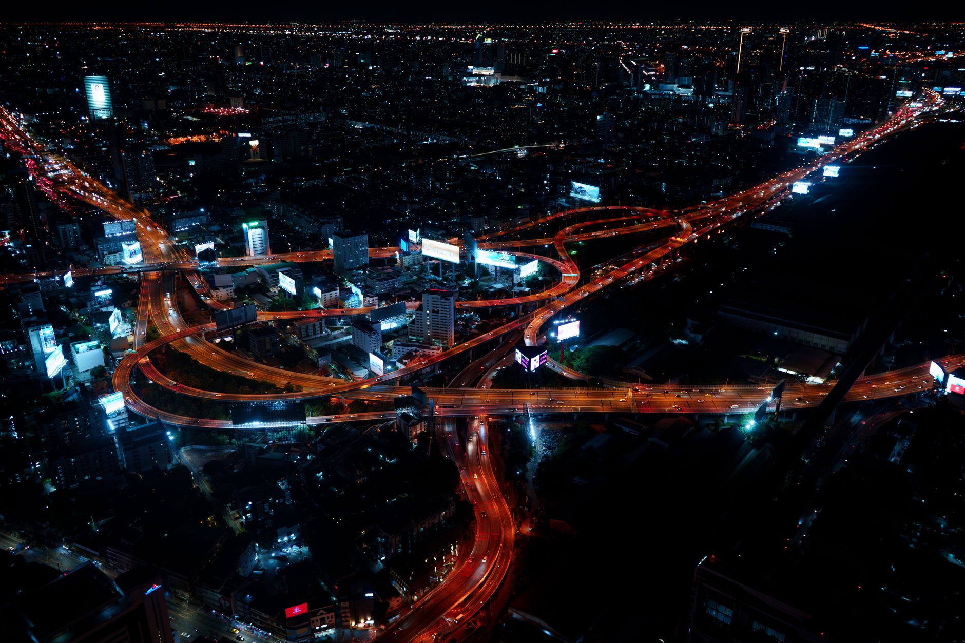 Aerial view of Bangkok's vibrant city lights and roads at night.