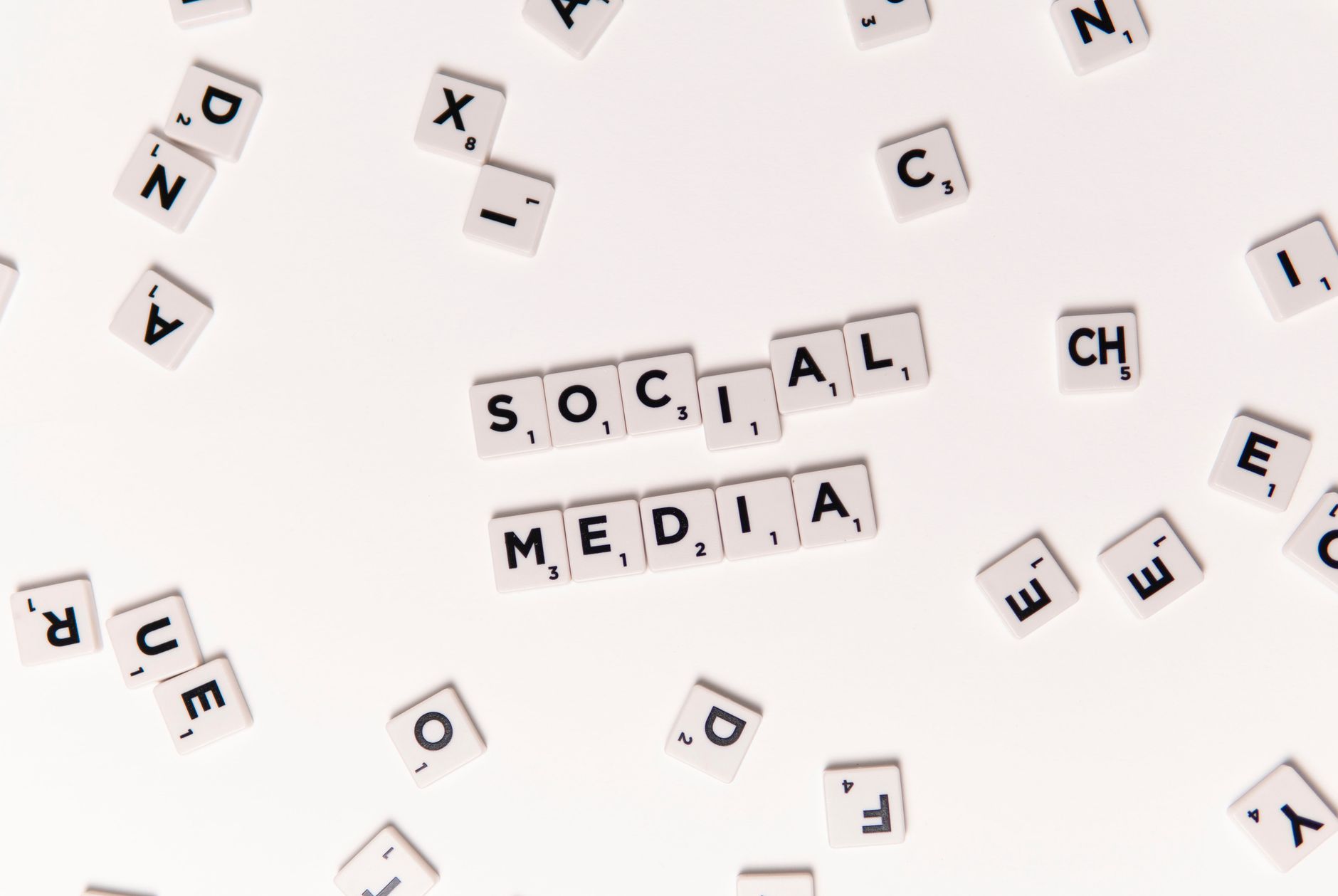 Flat lay of letter tiles spelling Social Media with scattered white tiles on a surface.