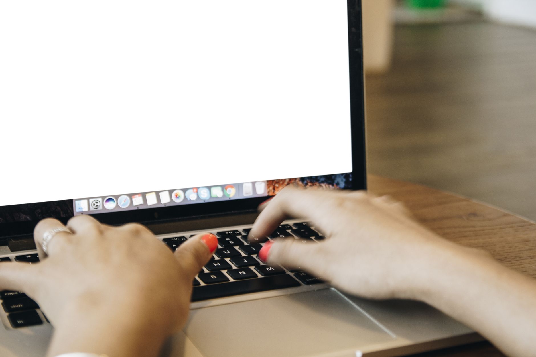 Close-up of female hands typing on a laptop in a cozy home office workspace, emphasizing technology and communication.