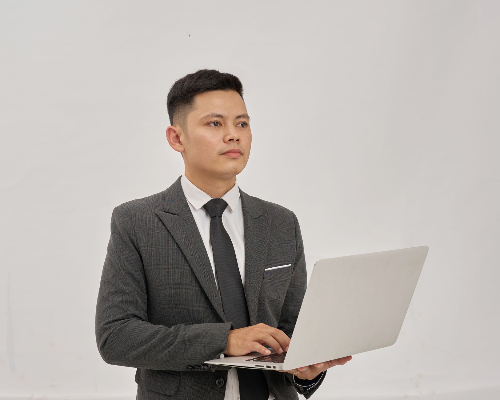 Confident business professional in a suit using a laptop in a bright indoor setting.