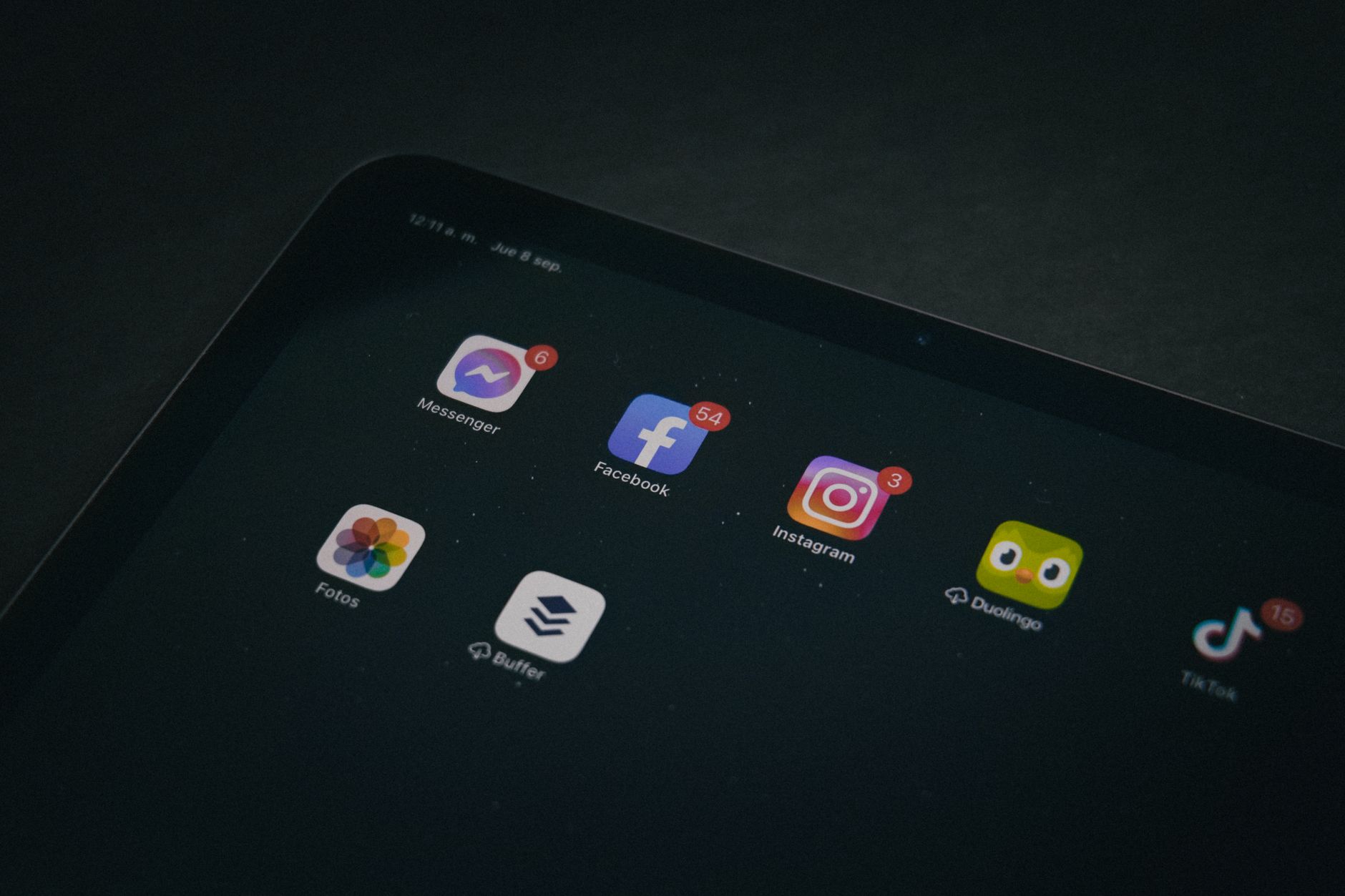 A tablet displaying popular apps like Facebook and Instagram in a dimly lit setting.