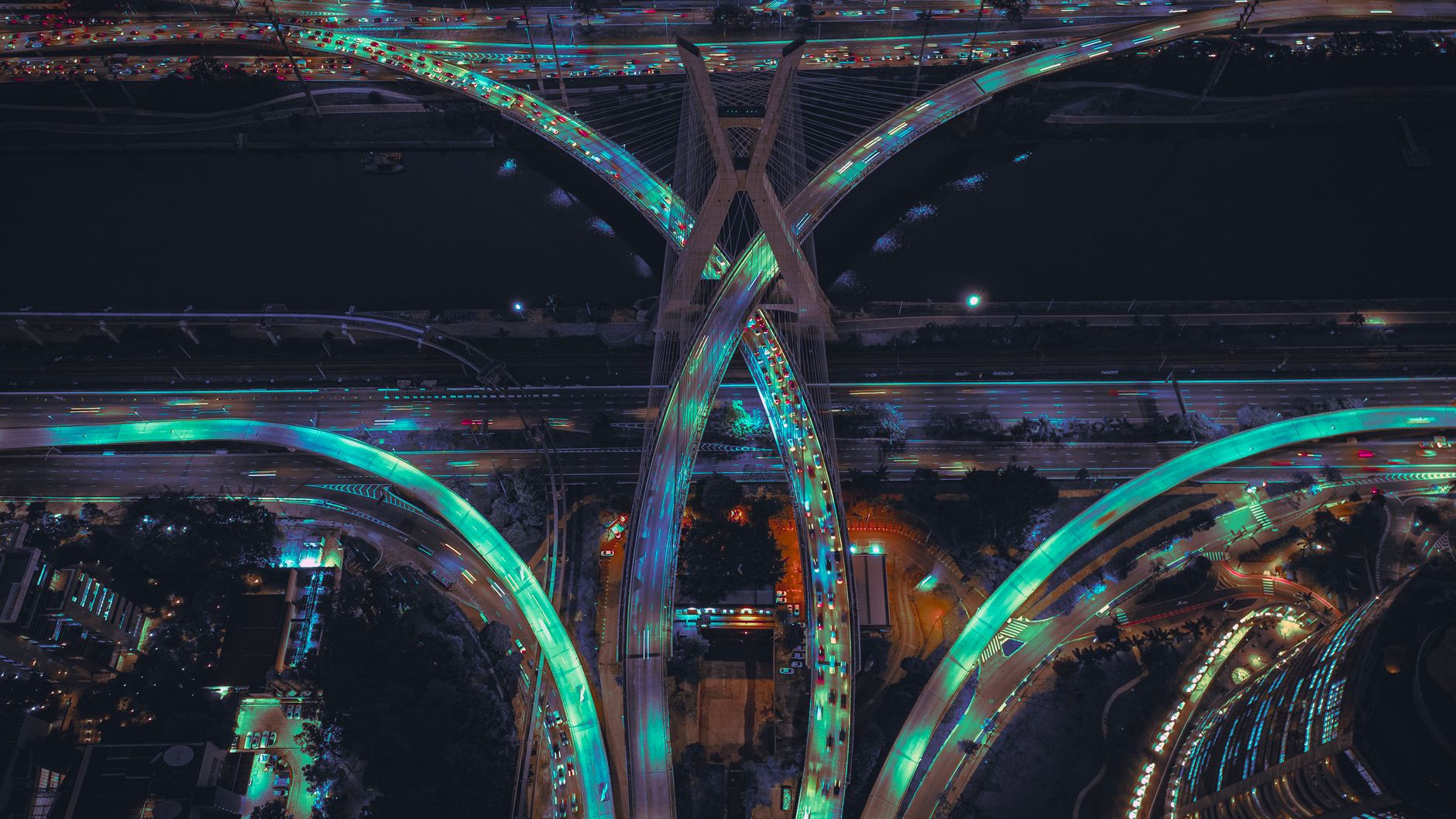 A stunning aerial view of illuminated highways and a cable-stayed bridge at night.