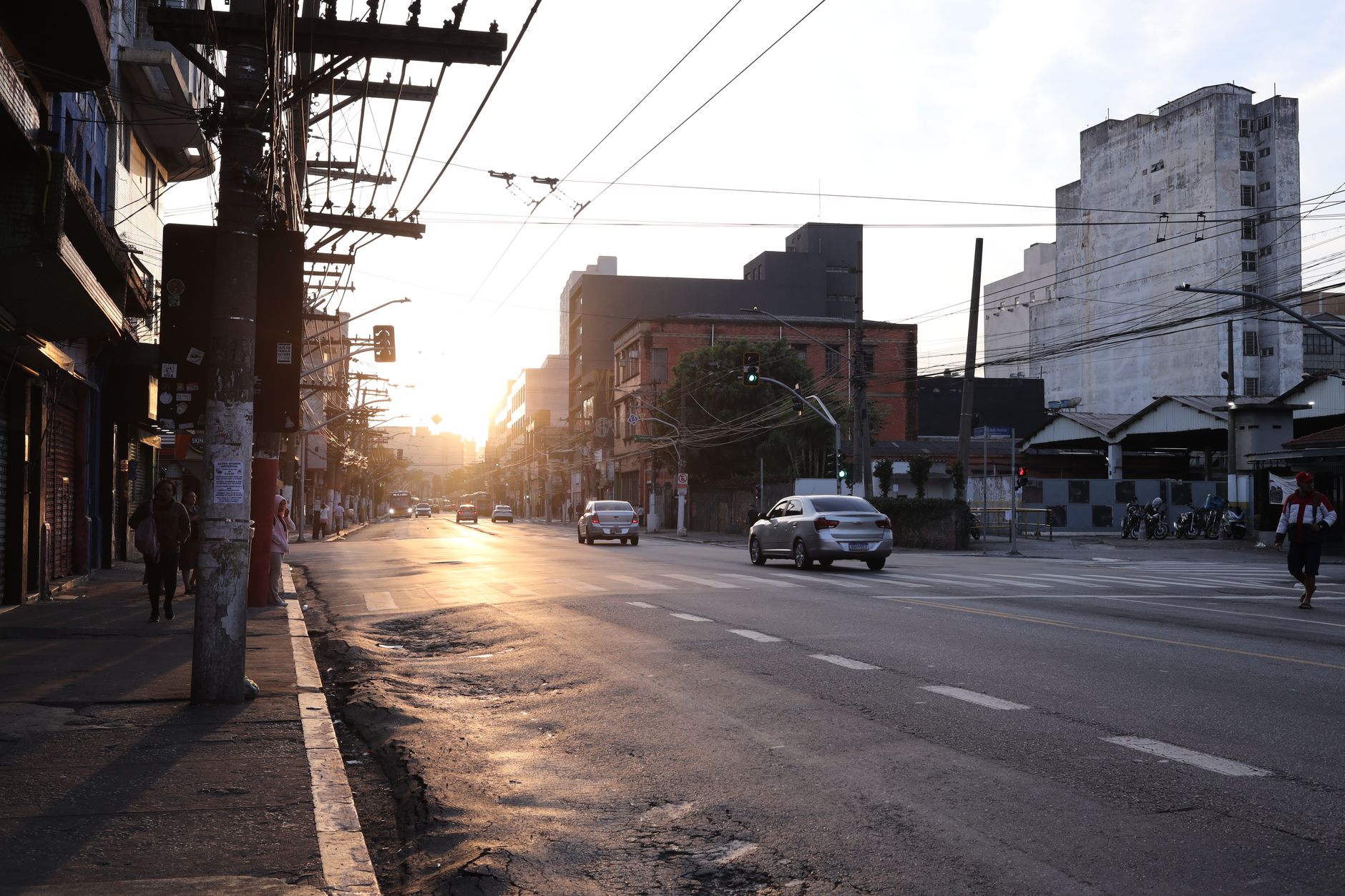 A vibrant city street with cars and pedestrians during sunset, creating a warm urban vibe.