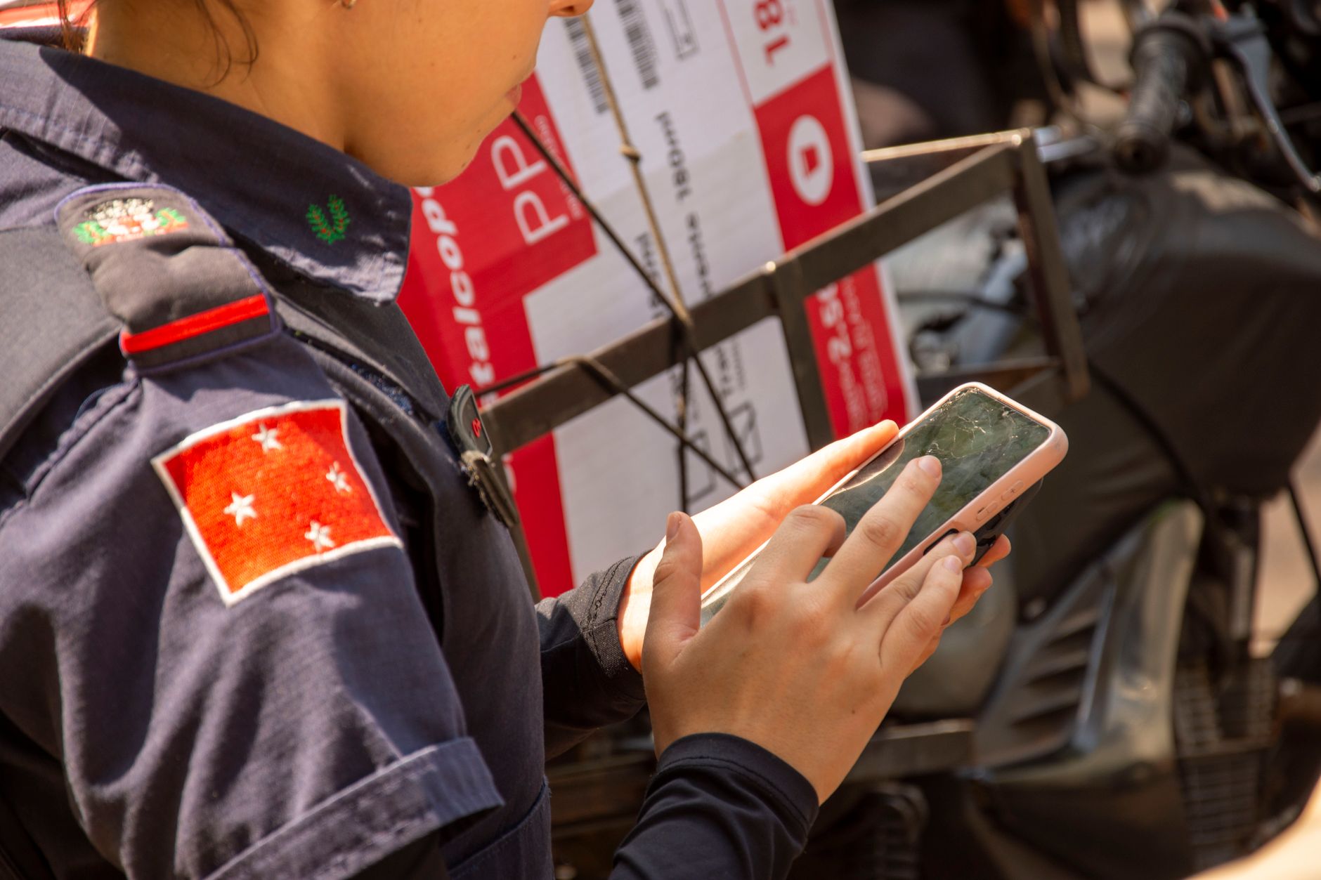 Police officer in uniform using smartphone outdoors in Londrina, Brazil.