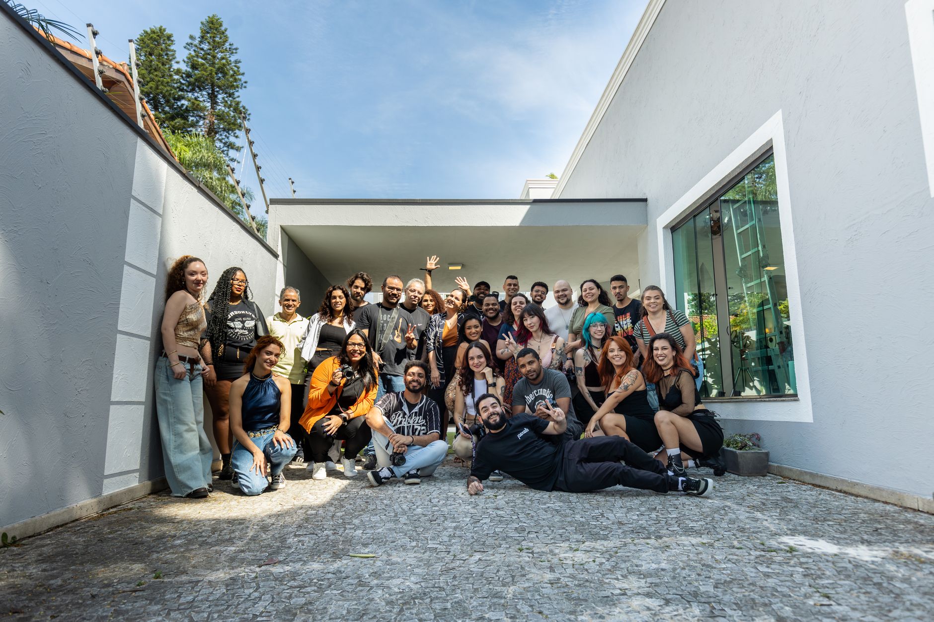 A diverse group posing happily outdoors in front of a modern building on a sunny day.