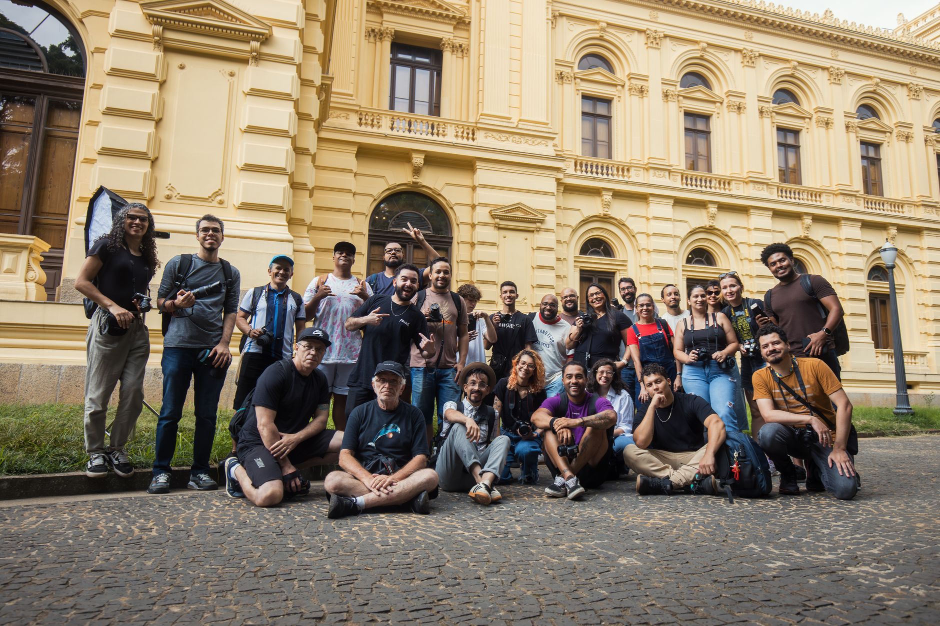 A diverse group of people gathered outside a historic yellow building, celebrating photography.