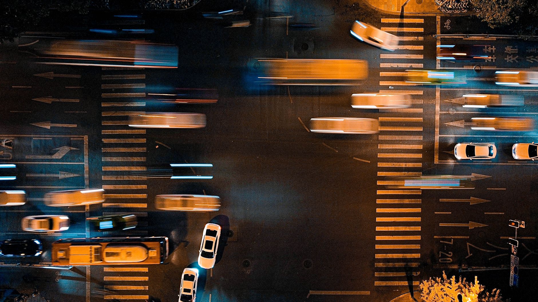 Aerial view of a city intersection at night with blurred motion of cars, showcasing urban life.