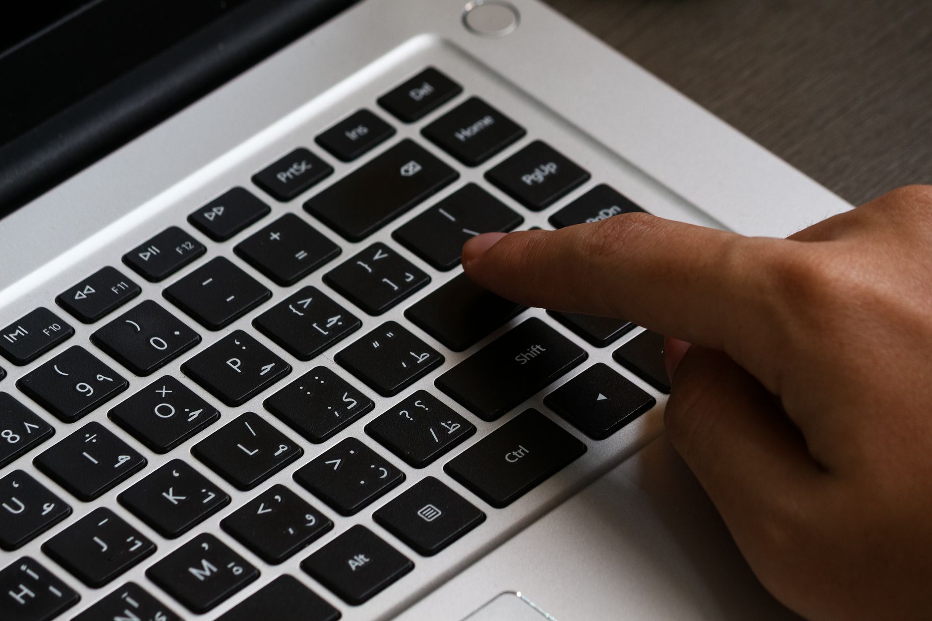 A person typing on a laptop keyboard with Arabic text, highlighting modern technology and digital workspace.