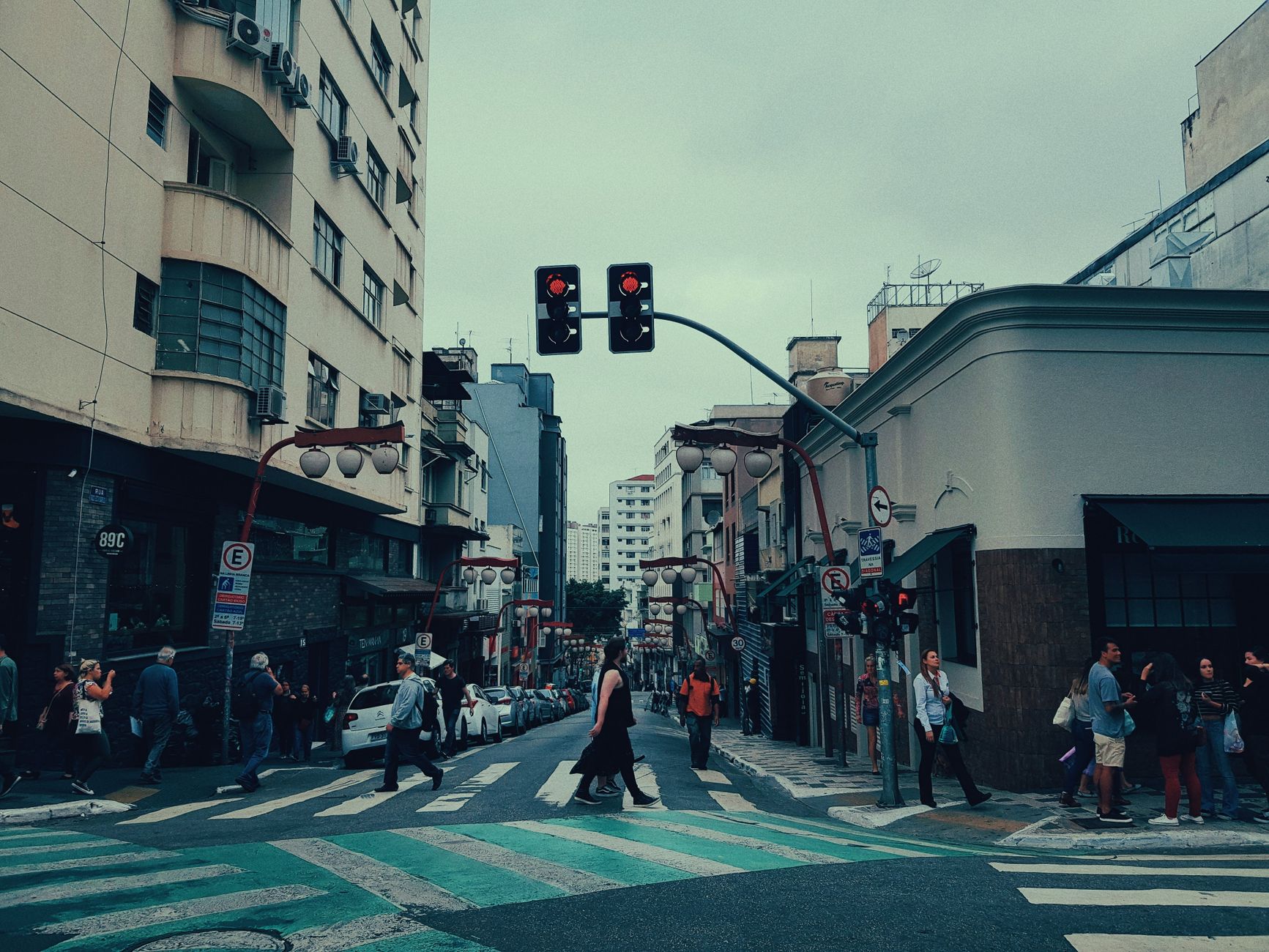 Asphalt street with pedestrian crossing and unrecognizable walking people near modern buildings in city district