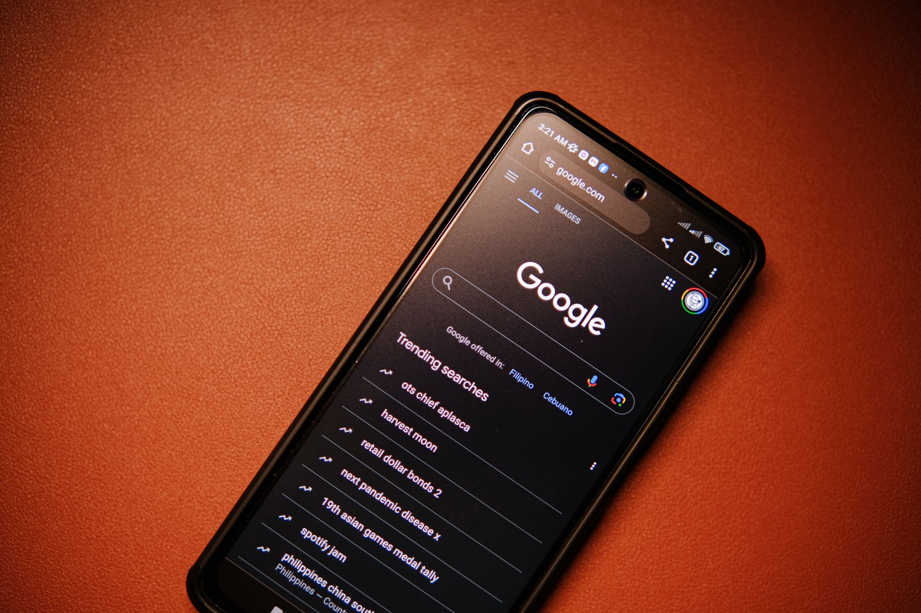 A smartphone displaying Google Search trends on a table at night.