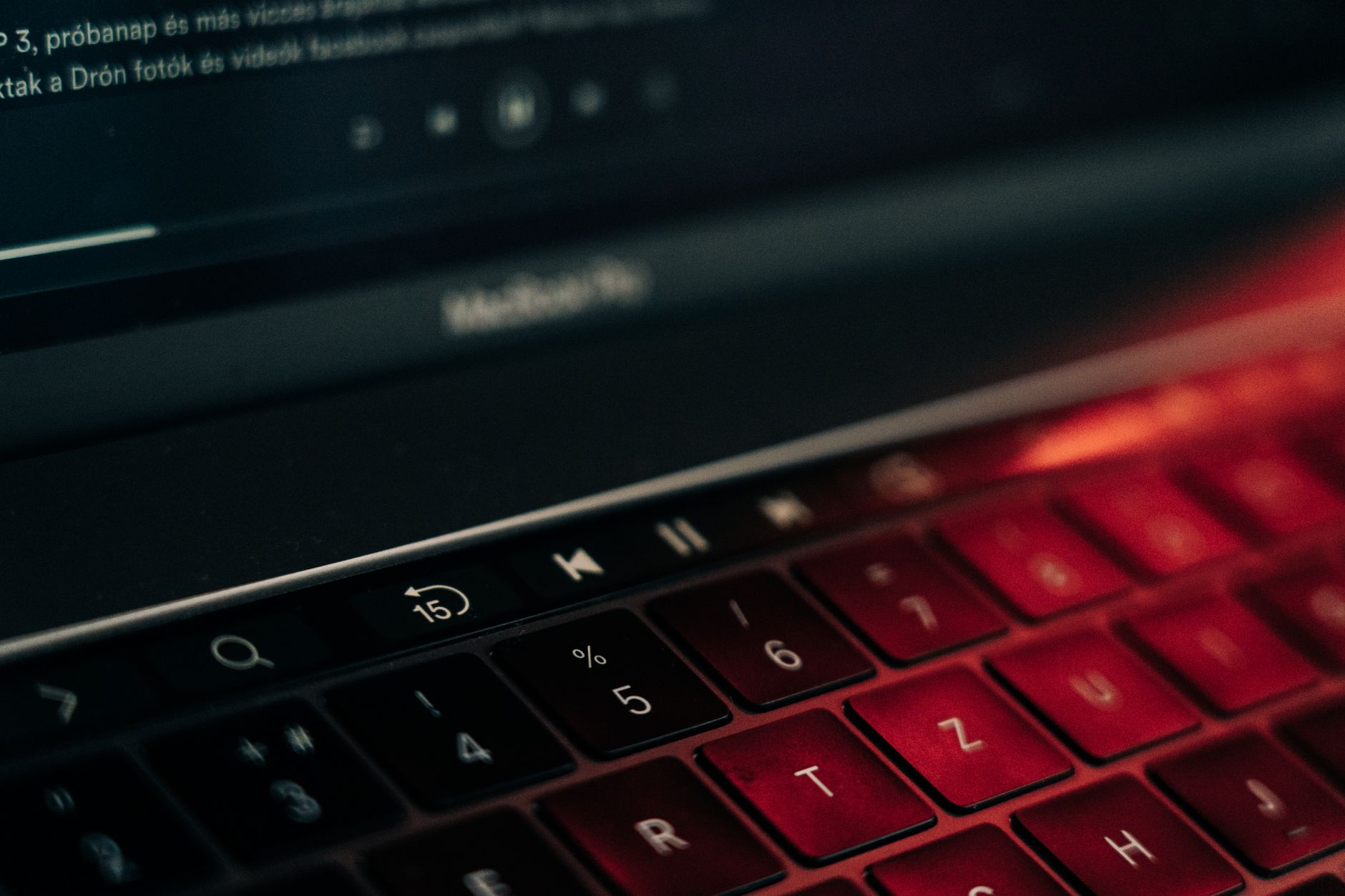 A vibrant close-up of a backlit laptop keyboard with a glowing red hue, showcasing modern technology.