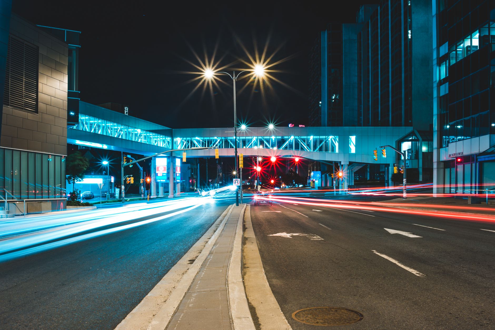 Asphalt road going through illuminated buildings located on city street at night time