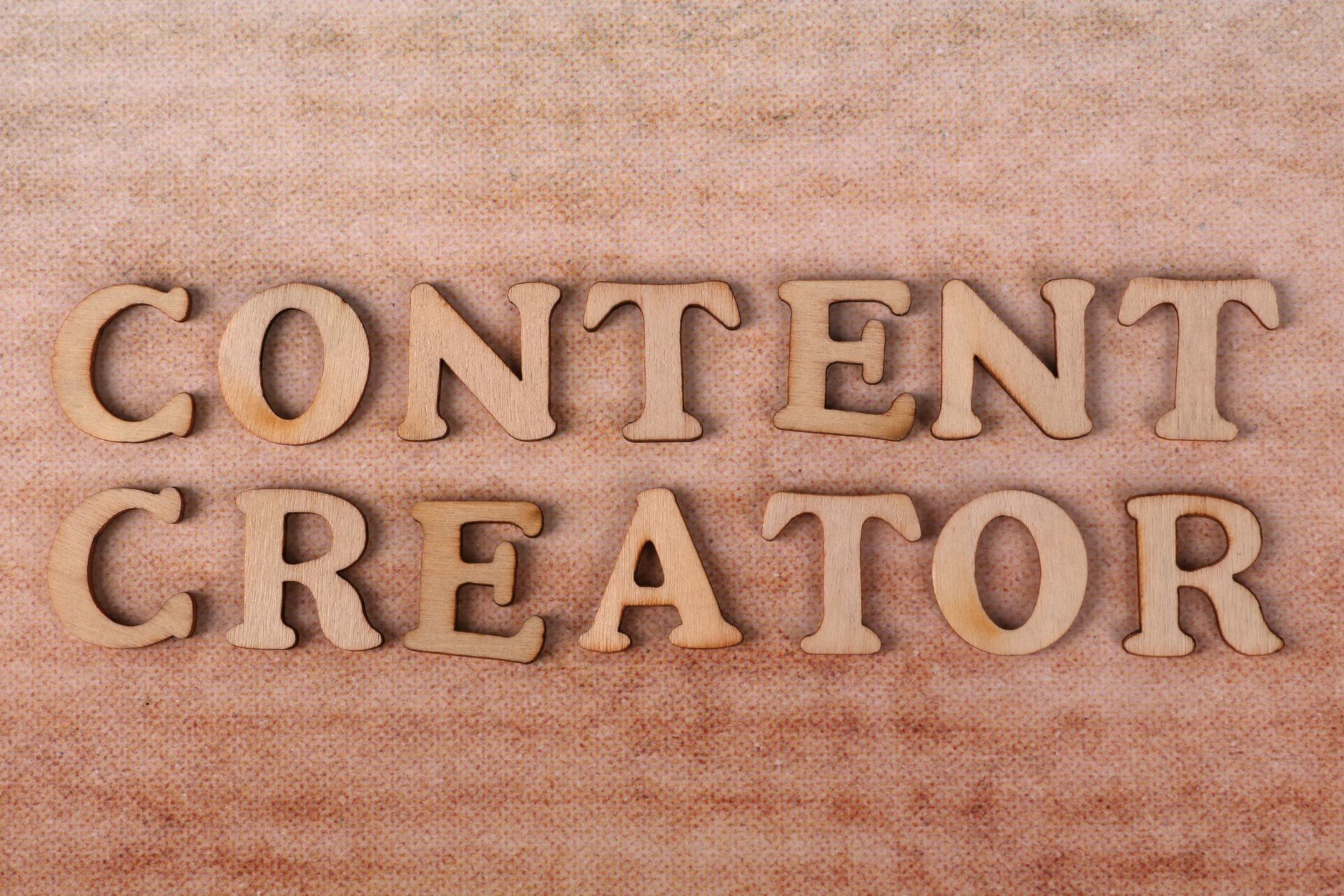 Wooden letters form 'Content Creator' on textured fabric background.